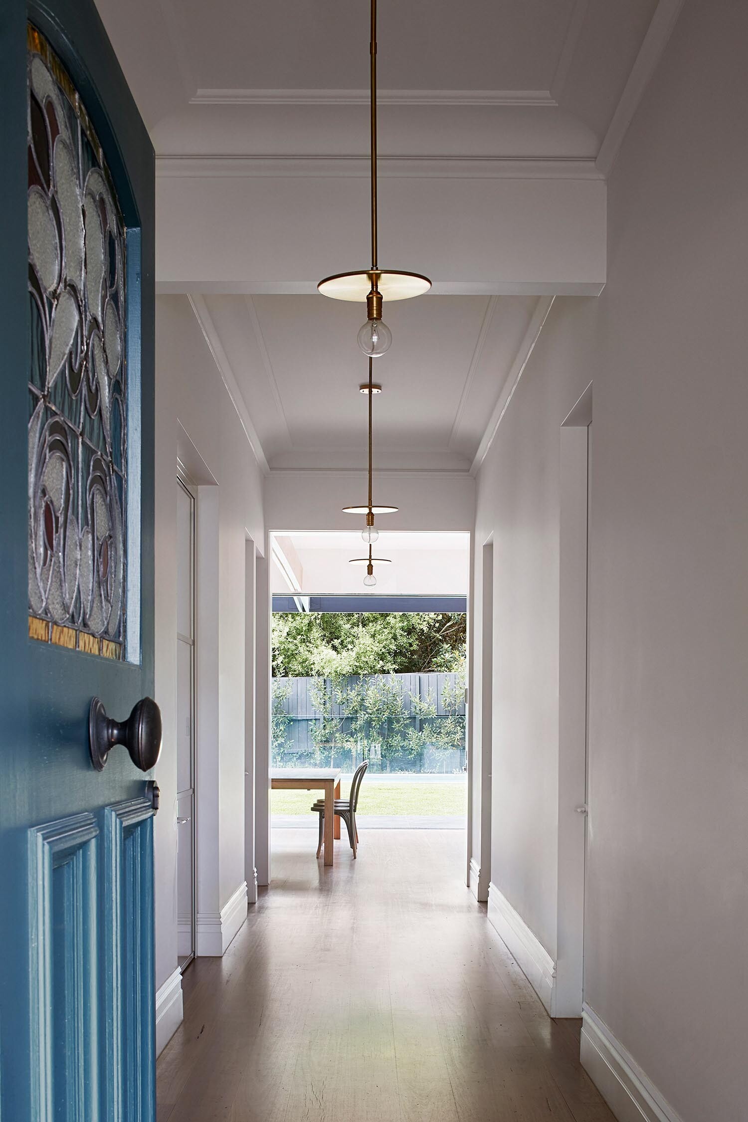 A bright entry hallway with clean lighting and warm wood floors that gently updates a traditional Federation interior.
