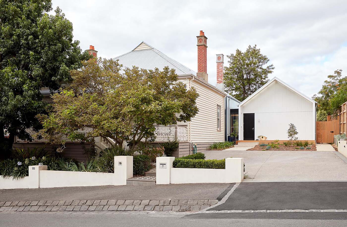A heritage street frontage hides a bold rear transformation, where twin gable roofs define a modern extension with layered outdoor spaces.