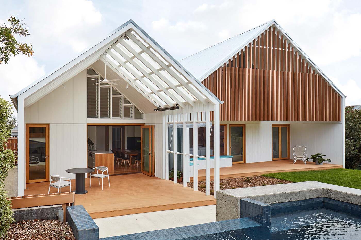 A heritage street frontage hides a bold rear transformation, where twin gable roofs define a modern extension with layered outdoor spaces.