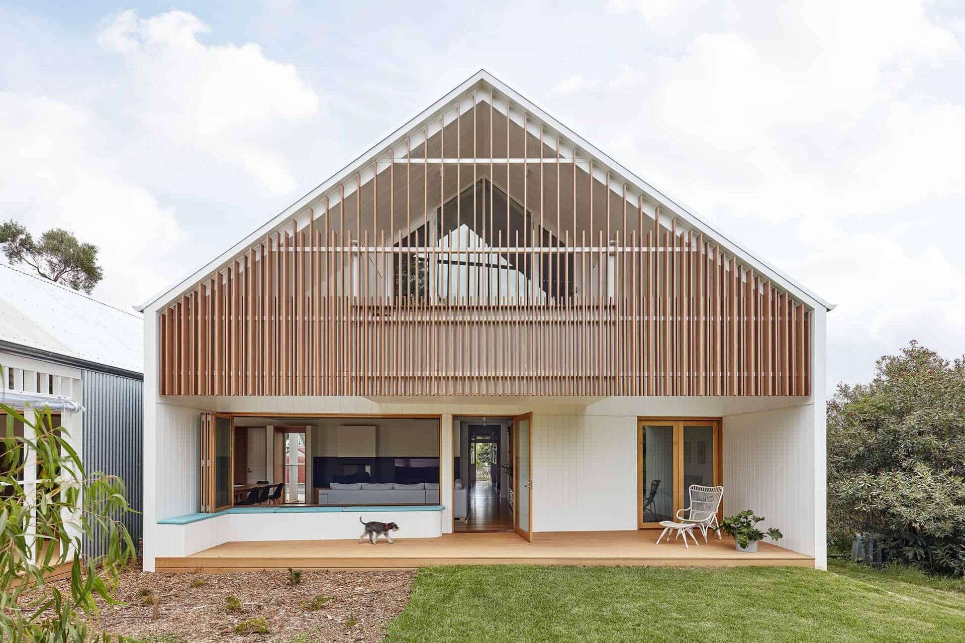 A heritage street frontage hides a bold rear transformation, where twin gable roofs define a modern extension with layered outdoor spaces.