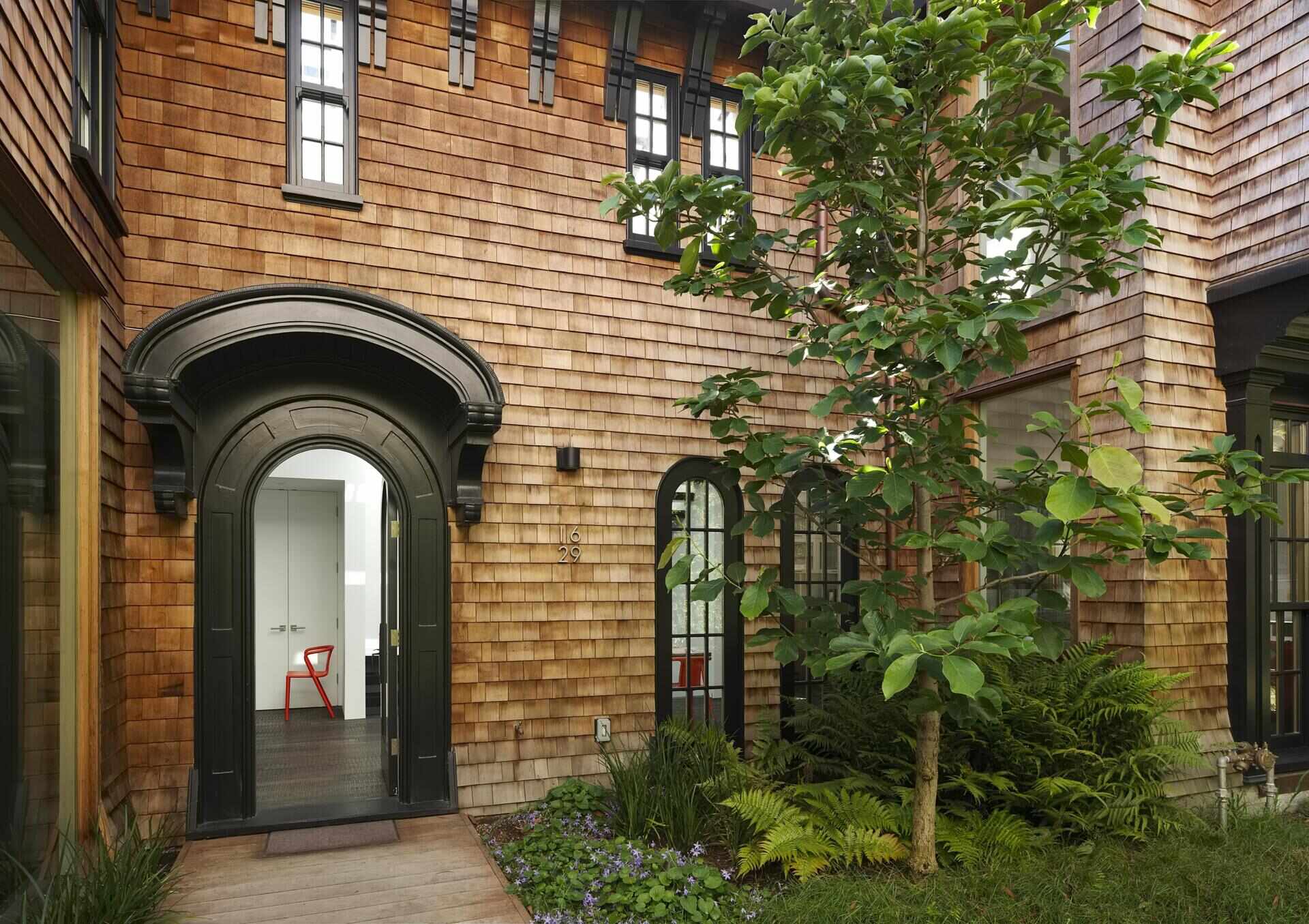 A restored 1917 facade in San Francisco featuring cedar shakes, black detailing, and heritage windows with subtle modern upgrades.