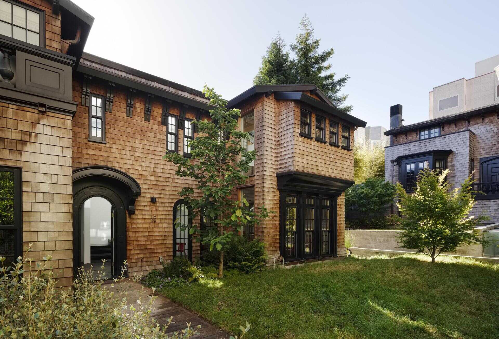 A restored 1917 facade in San Francisco featuring cedar shakes, black detailing, and heritage windows with subtle modern upgrades.