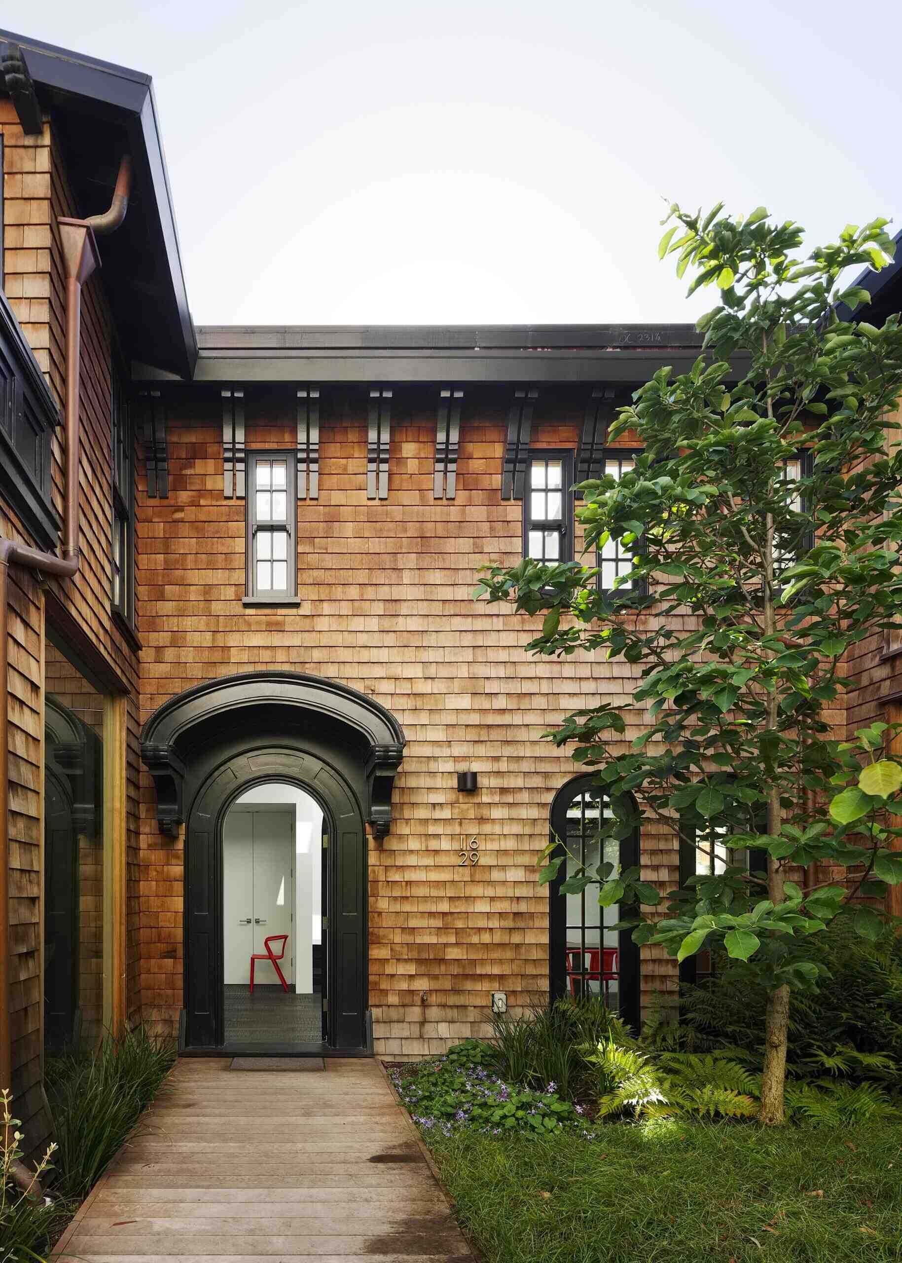 A restored 1917 facade in San Francisco featuring cedar shakes, black detailing, and heritage windows with subtle modern upgrades.