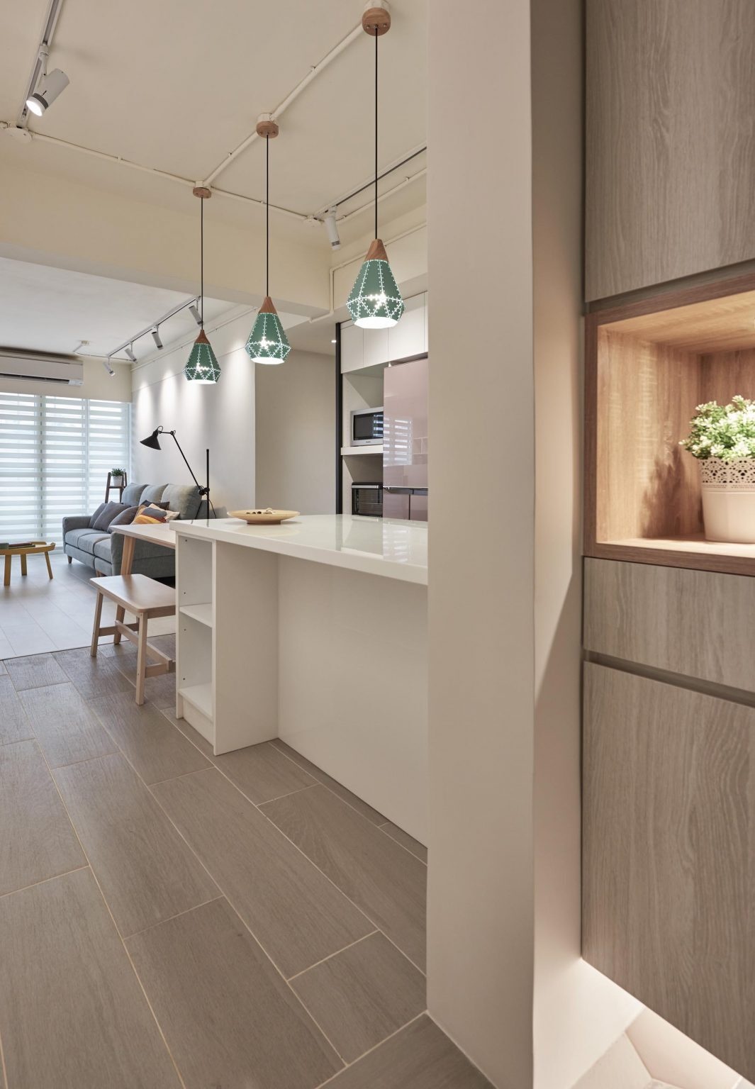 A bright white kitchen with handle-free cabinets, geometric pendant lighting, and a peninsula that flows into a dining table.