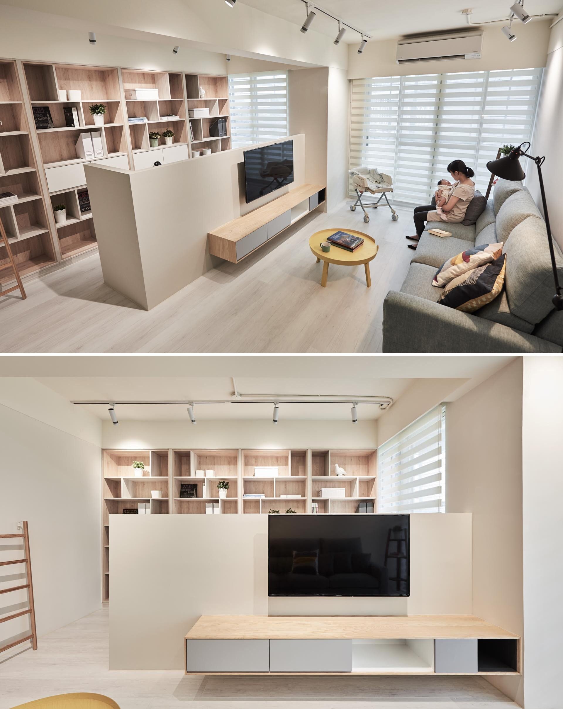 A living room in Taiwan that doubles as a home office, featuring a hidden desk, wood-lined bookshelves, and a sleek floating TV wall.