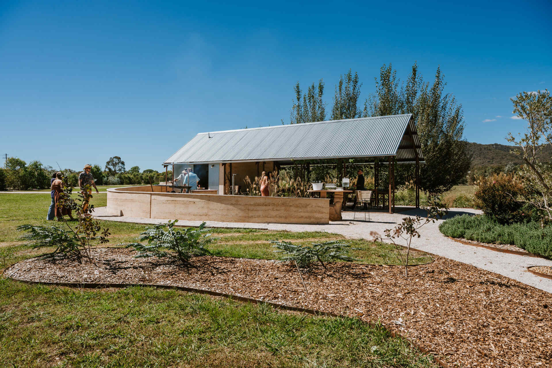 An intimate open-air events space in Australia where rammed earth, timber, and fire create a relaxed setting for gatherings and long-table dining.