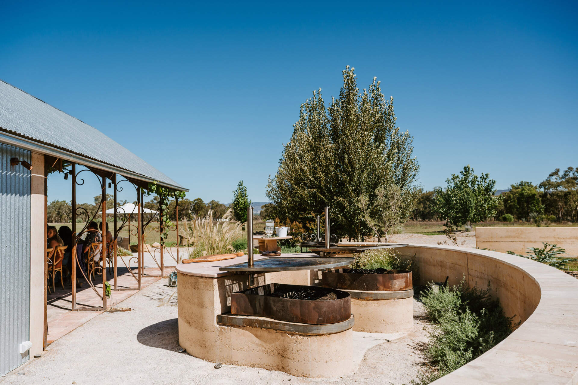 An intimate open-air events space in Australia where rammed earth, timber, and fire create a relaxed setting for gatherings and long-table dining.