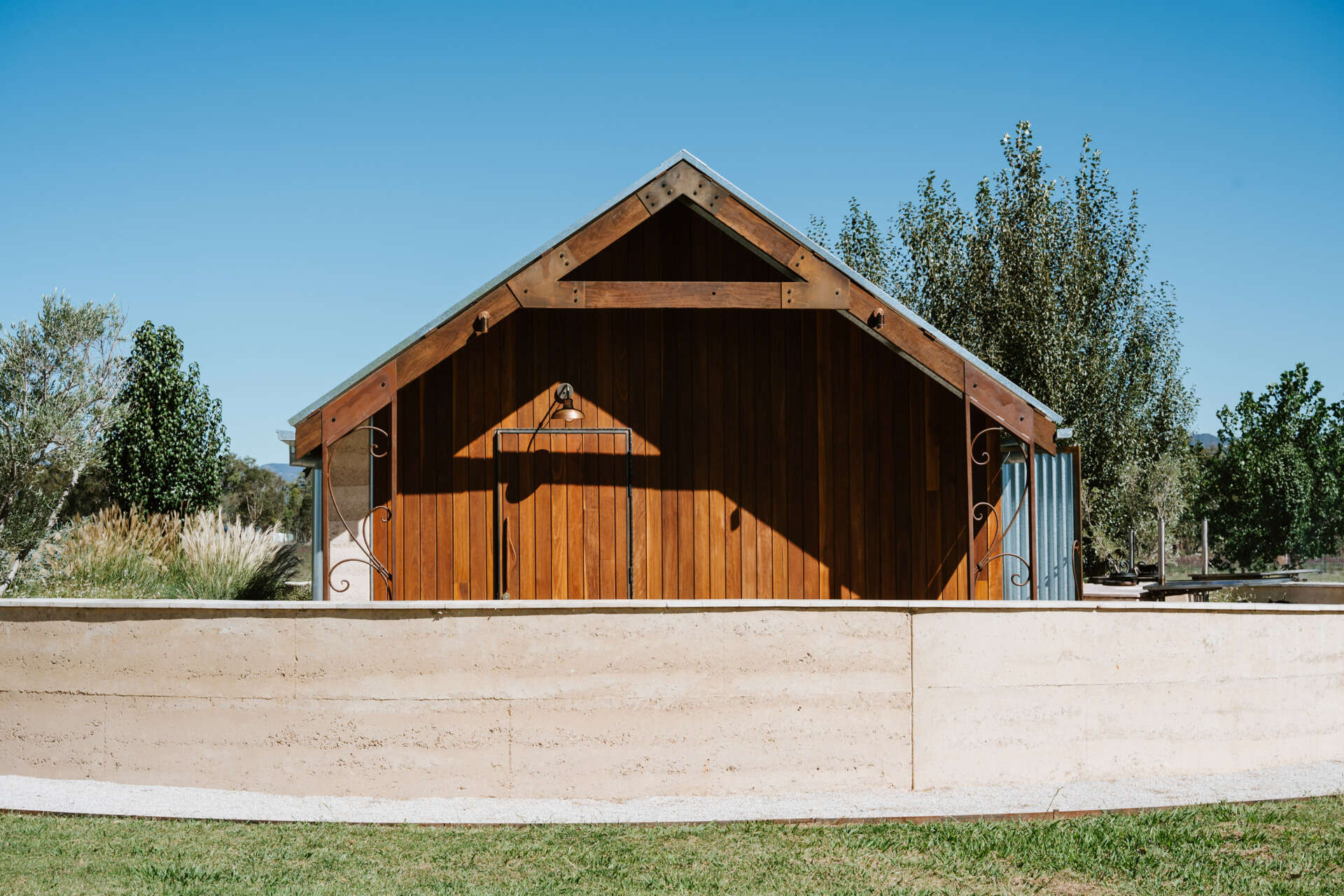 An intimate open-air events space in Australia where rammed earth, timber, and fire create a relaxed setting for gatherings and long-table dining.