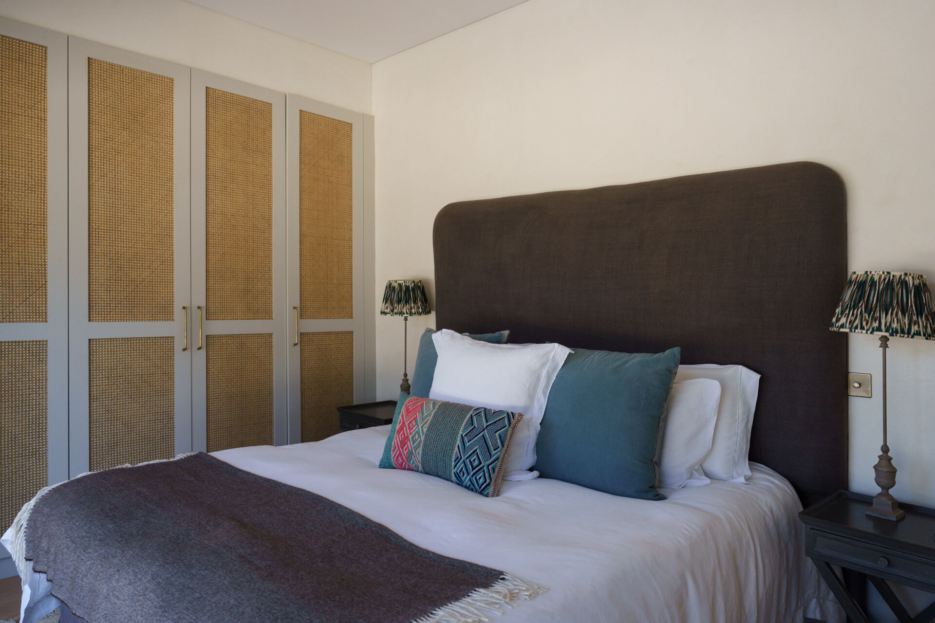 These minimalist bedrooms open toward sunrise views through the pine trees, with private terraces filled with rosemary, lavender, and Mediterranean greenery.