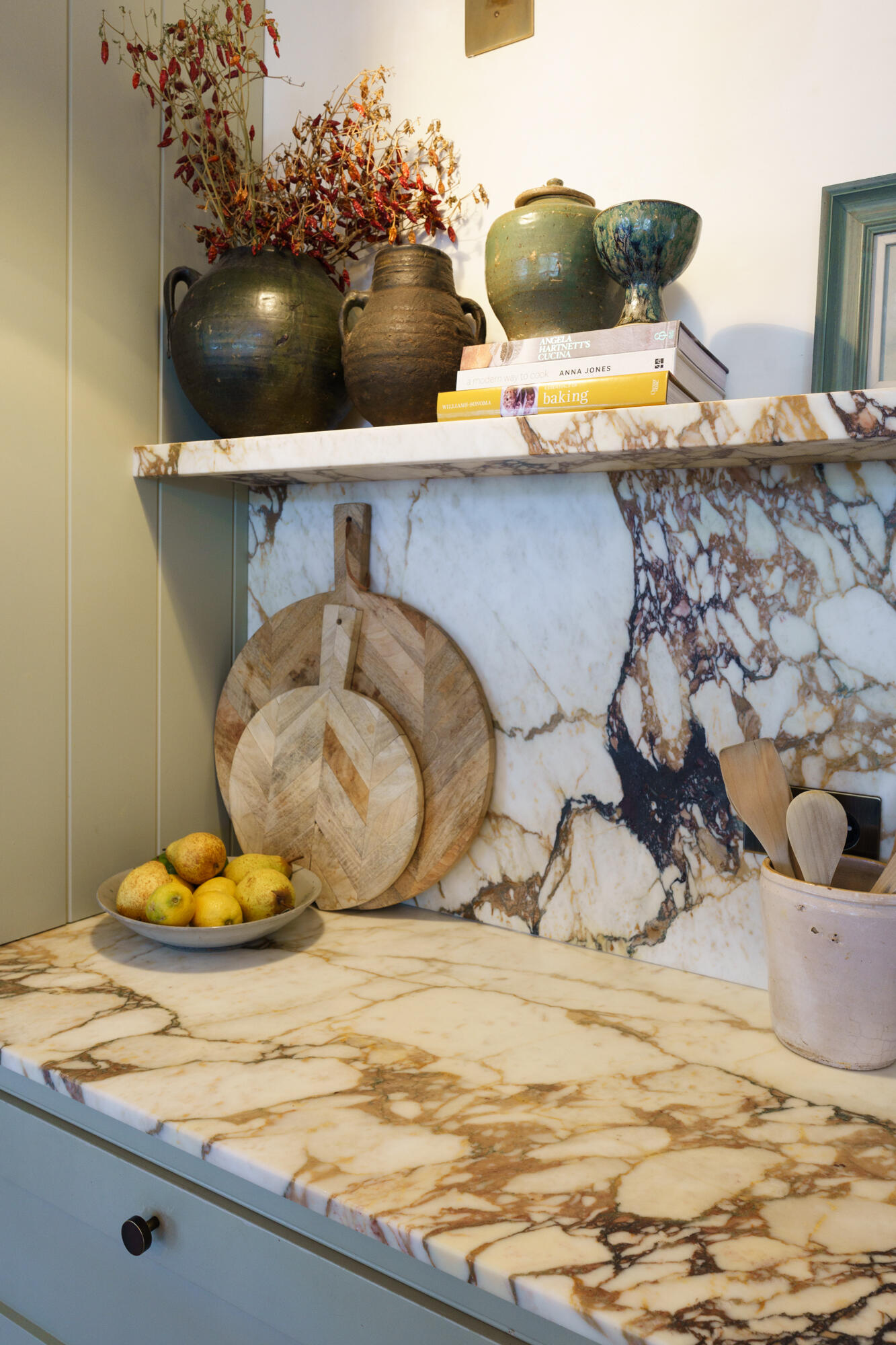 This contemporary kitchen combines sage cabinetry, dramatic marble, woven pendant lights, and a bold plum island for a warm Mediterranean-inspired look.