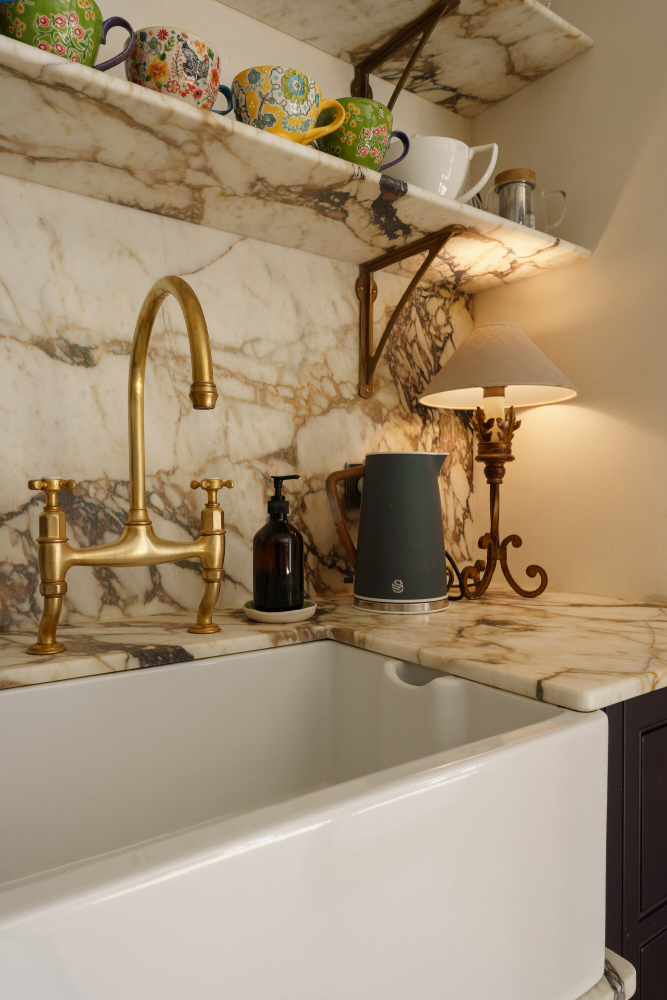 This contemporary kitchen combines sage cabinetry, dramatic marble, woven pendant lights, and a bold plum island for a warm Mediterranean-inspired look.