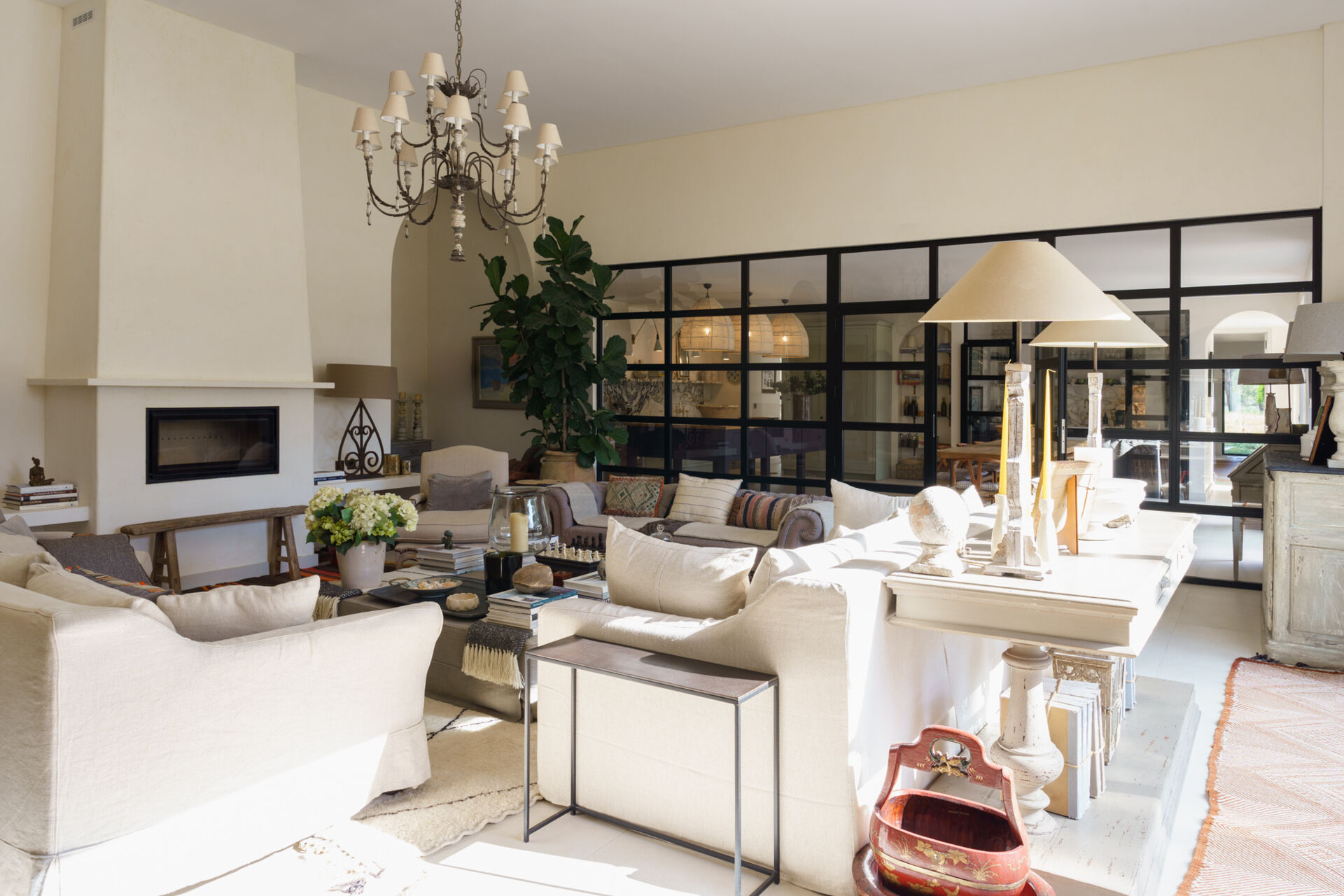 Inside the central wing of the villa, the living room opens completely toward the courtyard through expansive retractable glazing. The room feels constantly linked to the outdoors. Even when closed, the glass walls maintain uninterrupted views of trees, sand, and sky from nearly every angle.
