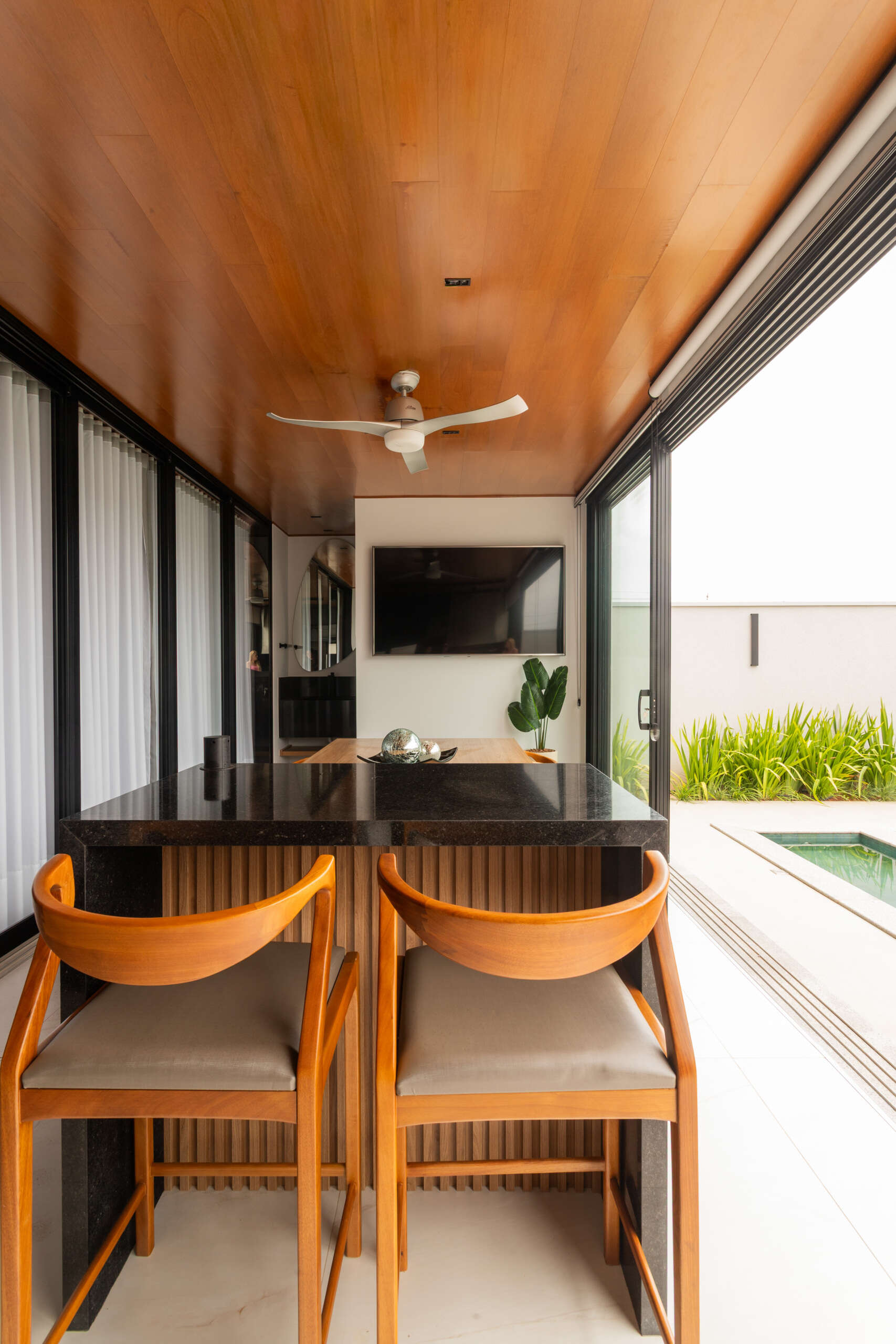 The covered outdoor dining and BBQ area at Casa R|L blends contemporary architecture with seamless indoor-outdoor entertaining in Brazil.