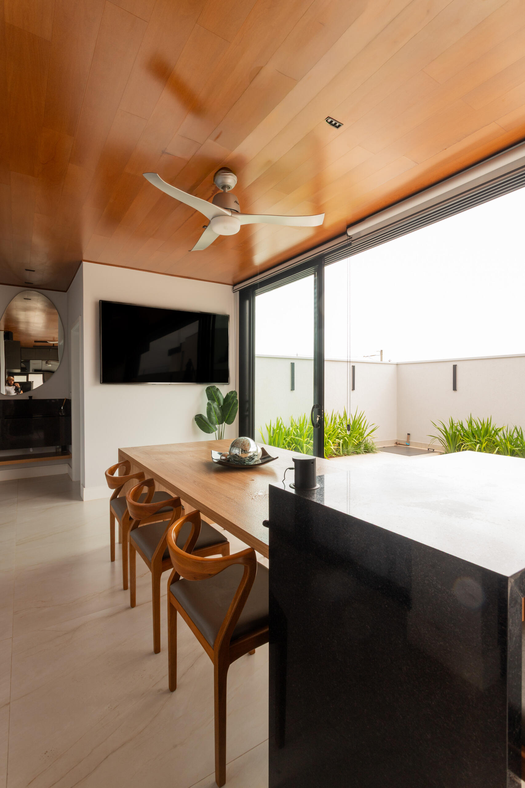 The covered outdoor dining and BBQ area at Casa R|L blends contemporary architecture with seamless indoor-outdoor entertaining in Brazil.