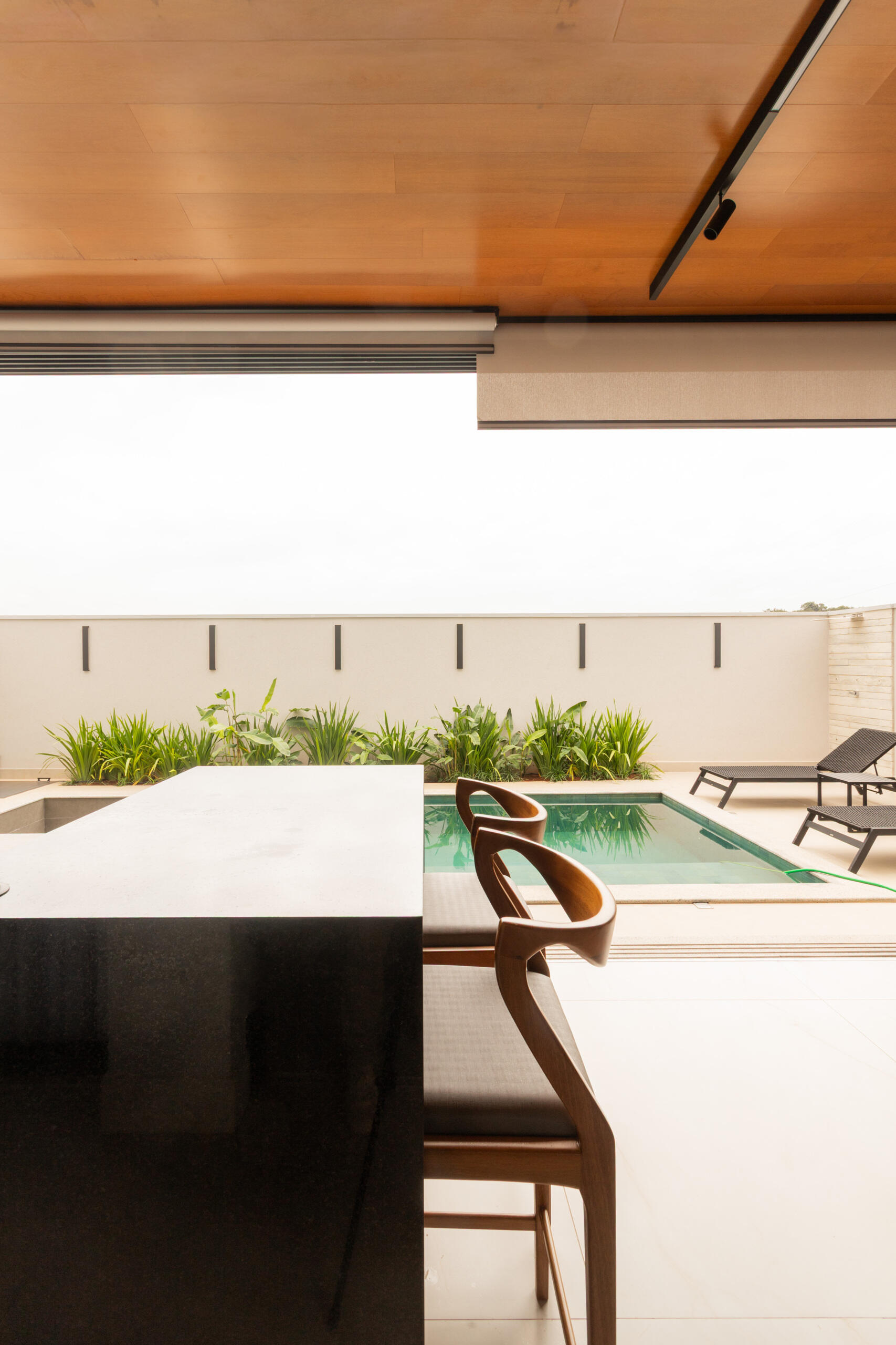 The covered outdoor dining and BBQ area at Casa R|L blends contemporary architecture with seamless indoor-outdoor entertaining in Brazil.
