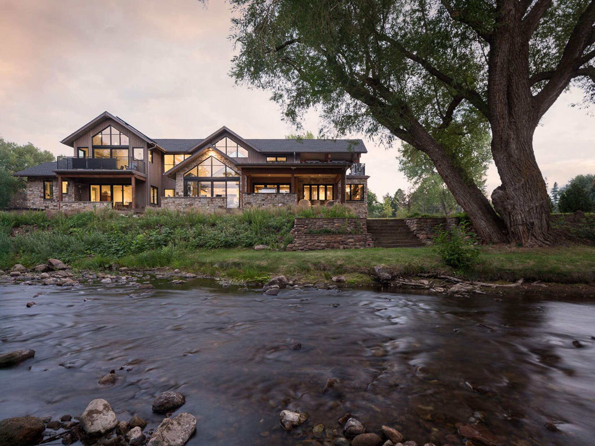 A modern mountain home in Boulder, Colorado combines timber, stone, and walls of glass to frame Flatirons views beside South Boulder Creek.