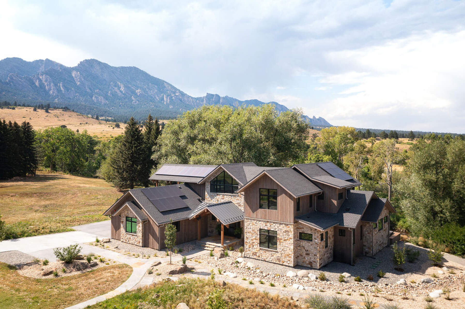 A modern mountain home in Boulder, Colorado combines timber, stone, and walls of glass to frame Flatirons views beside South Boulder Creek.