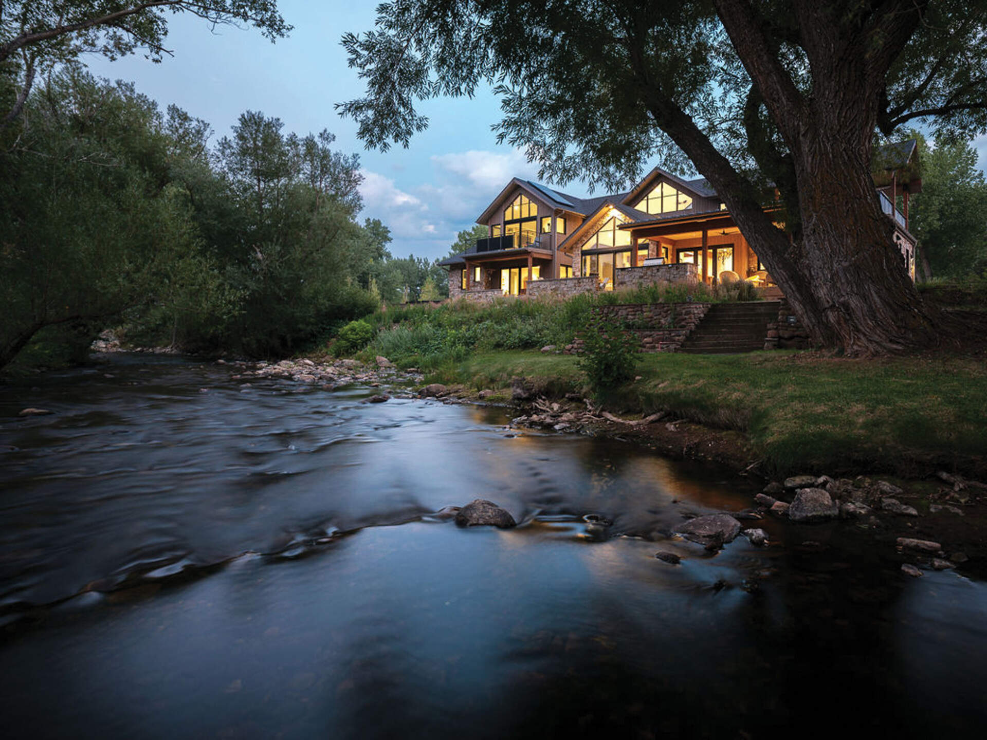 A modern mountain home in Boulder, Colorado combines timber, stone, and walls of glass to frame Flatirons views beside South Boulder Creek.