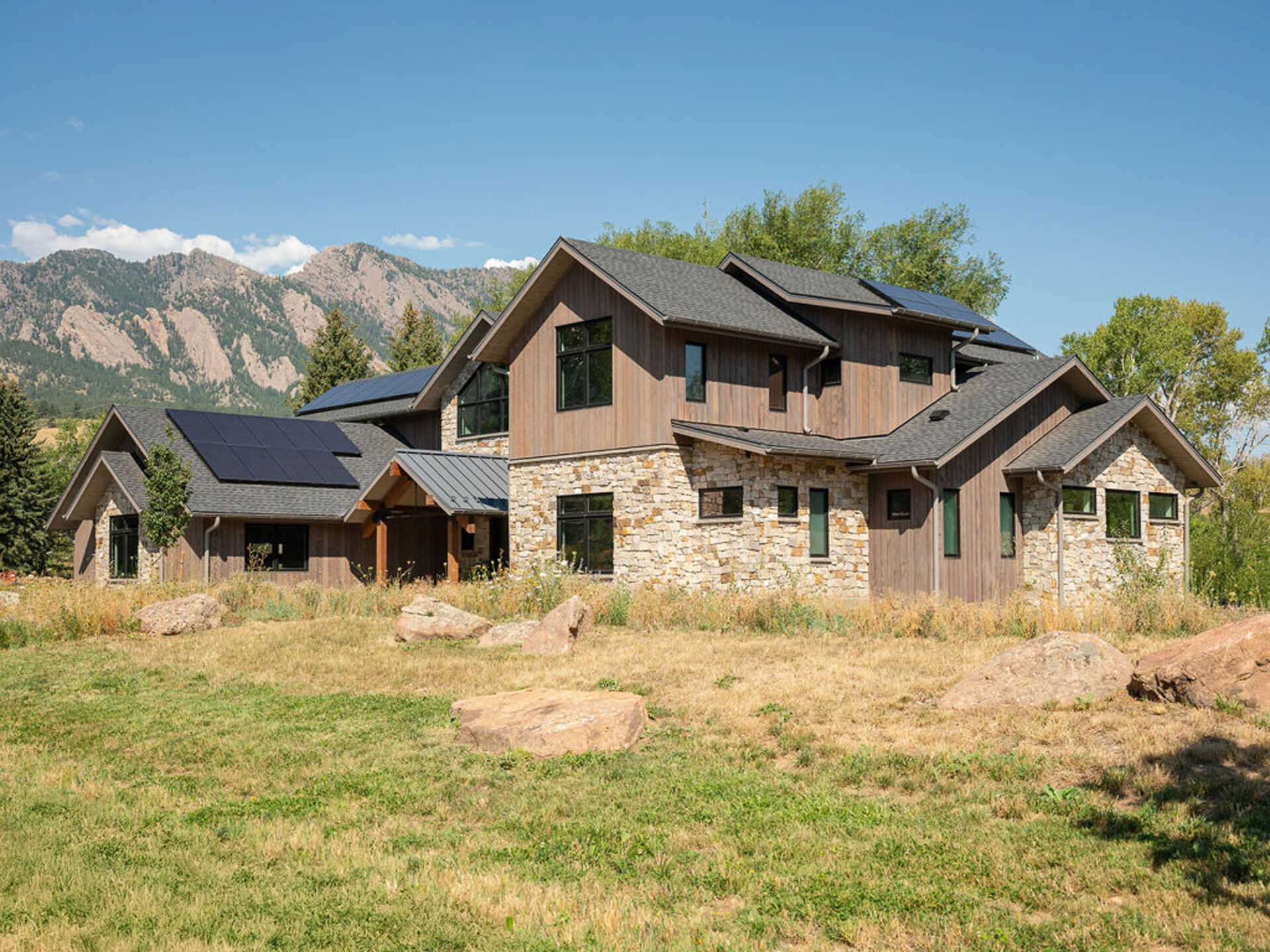A modern mountain home in Boulder, Colorado combines timber, stone, and walls of glass to frame Flatirons views beside South Boulder Creek.