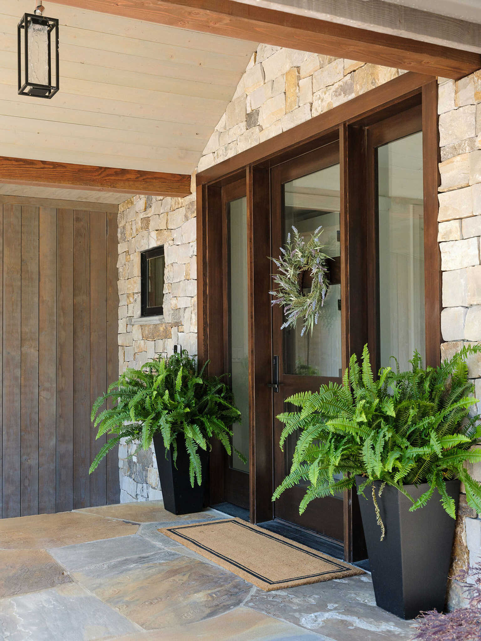 Stone walls, exposed timber beams, and dramatic gabled windows shape the welcoming entrance of this modern Boulder mountain home.