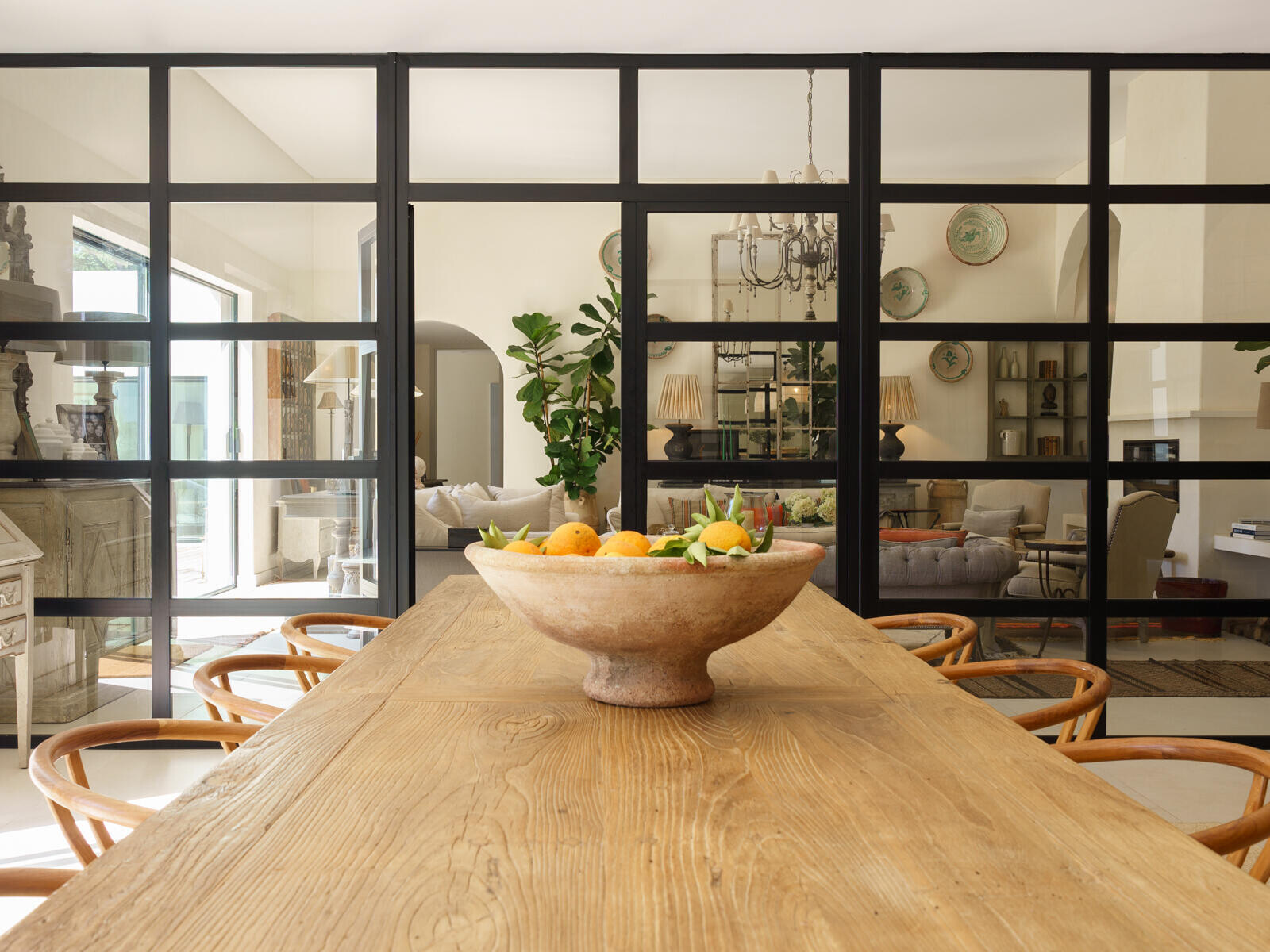 A black-framed glass room divider separates the living room from the dining area and kitchen.