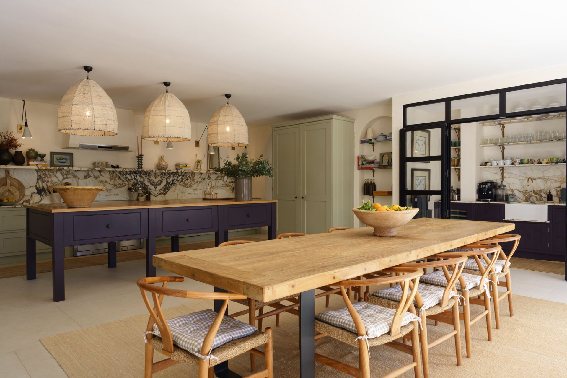 The dining space is separated from the living room by a black-framed glass wall, allowing for natural light to pass through and provide views of the living room.