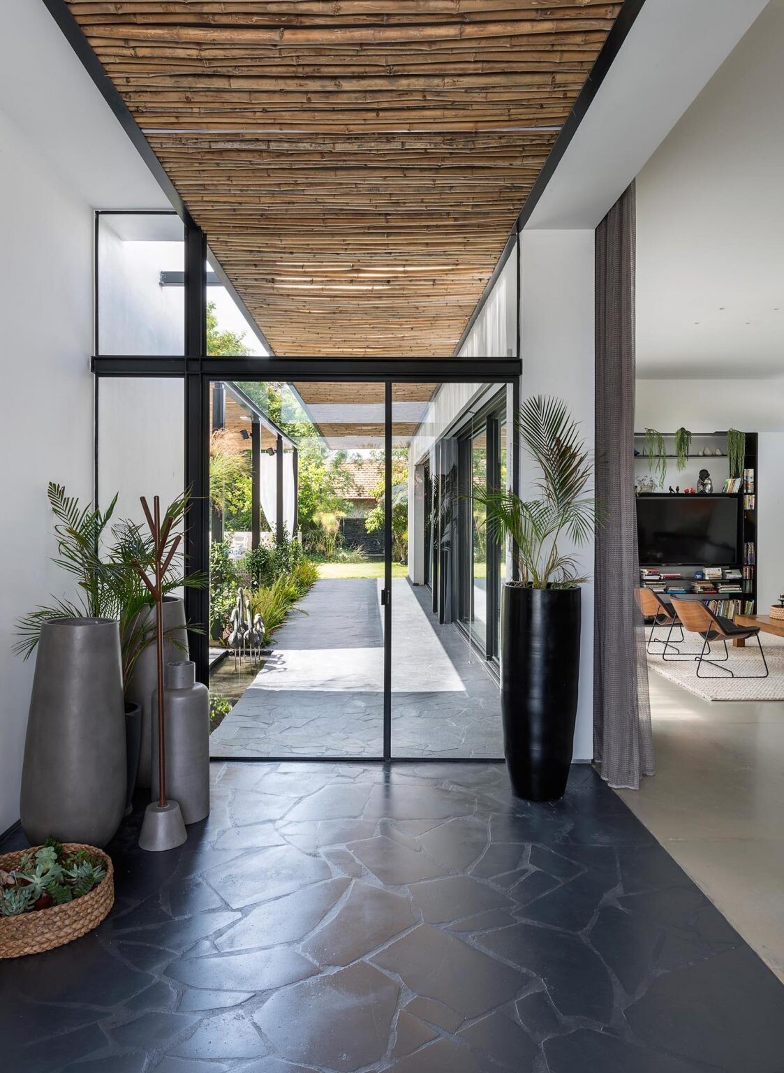 Bamboo screens and black accents create a warm, modern entrance for this contemporary home design.