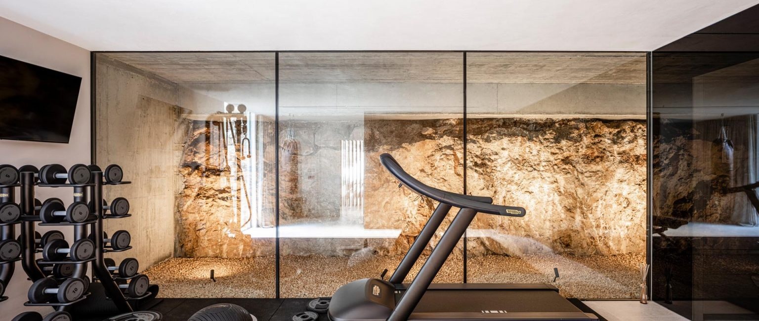 Floor-to-ceiling glass walls in this home gym showcase the natural rock formations found on the Mallorca property.