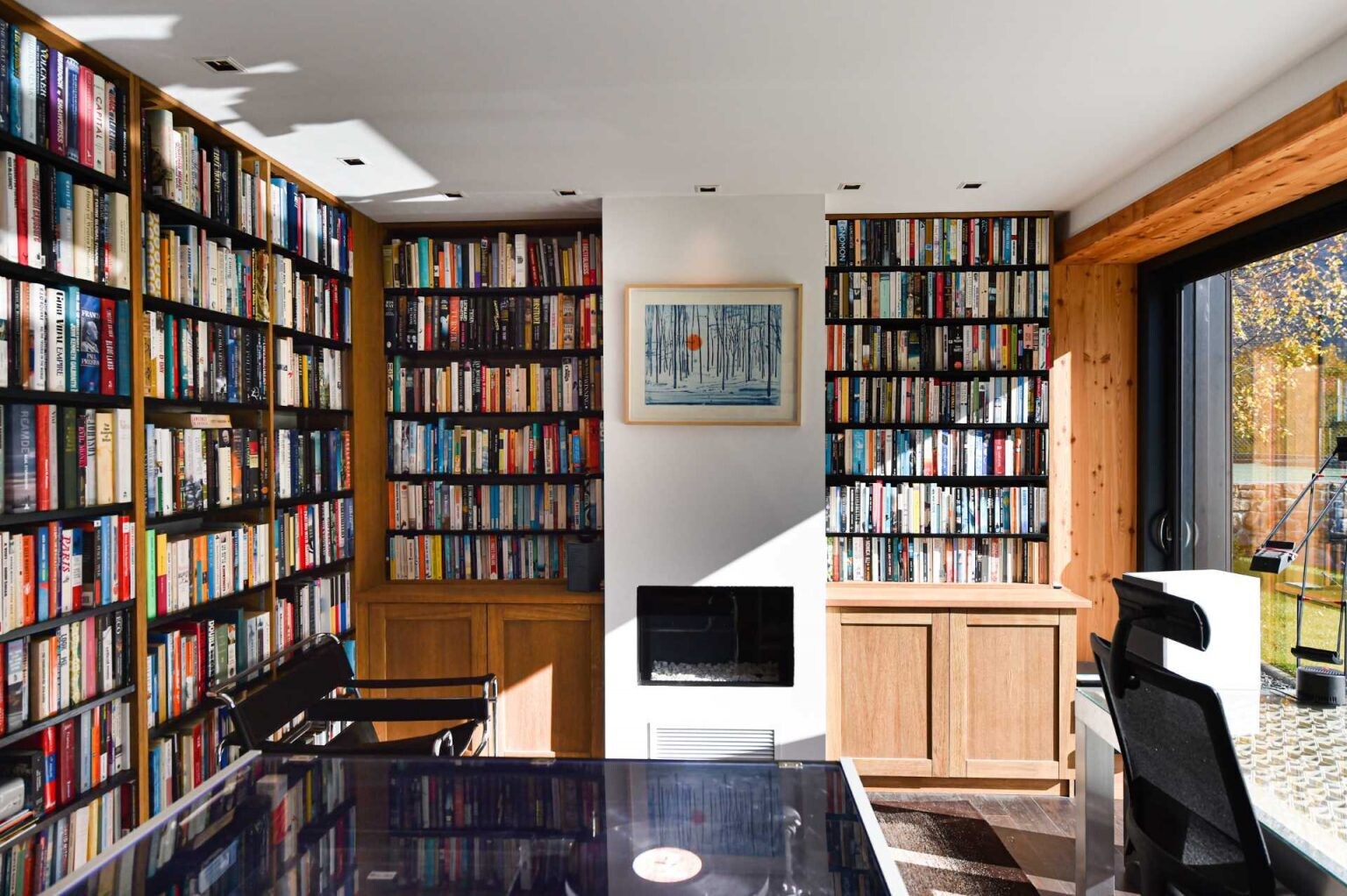 This cozy home library combines built-in shelving, a fireplace, and sliding glass doors that open directly onto the patio.