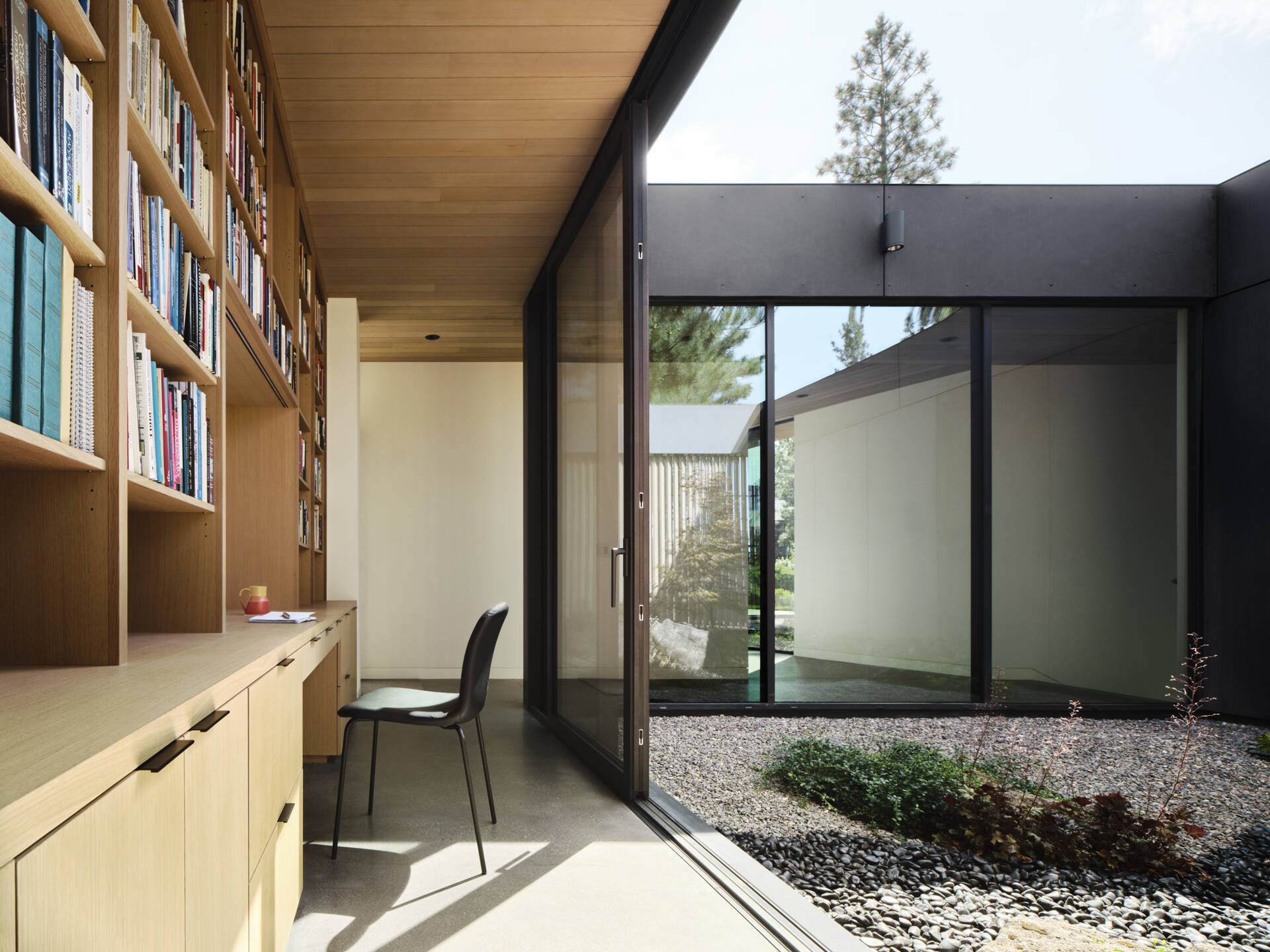 Private courtyards and expansive glazing bring soft natural light into this calm, modern home office space.