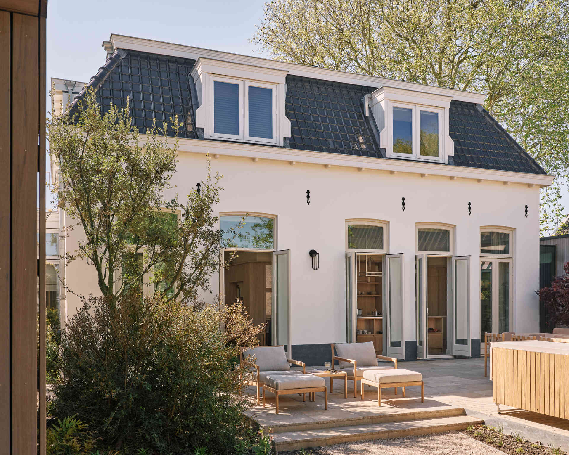This landscaped riverside garden features outdoor dining zones, light furniture, and beautiful views stretching across the Rijn.