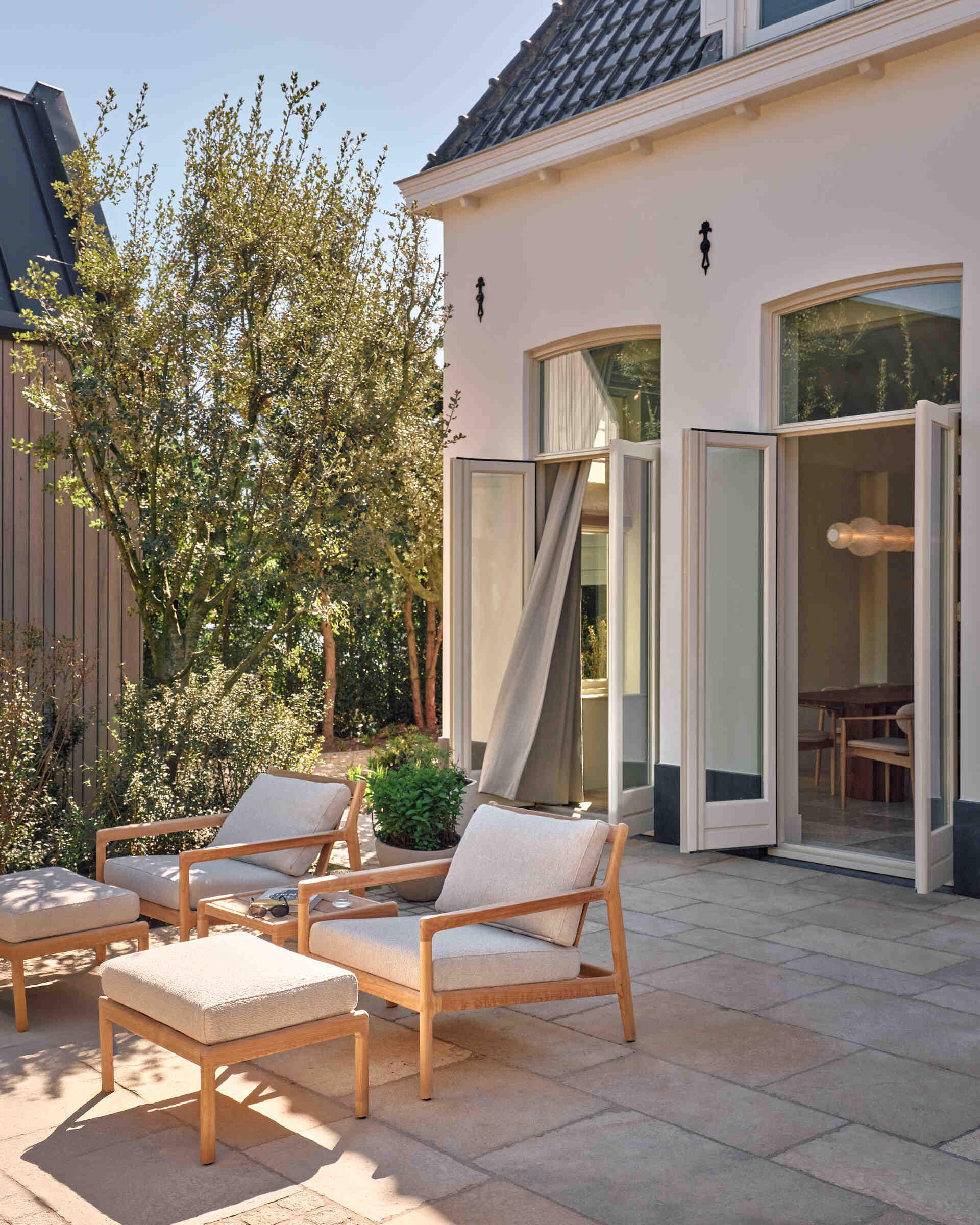 This landscaped riverside garden features outdoor dining zones, light furniture, and beautiful views stretching across the Rijn.