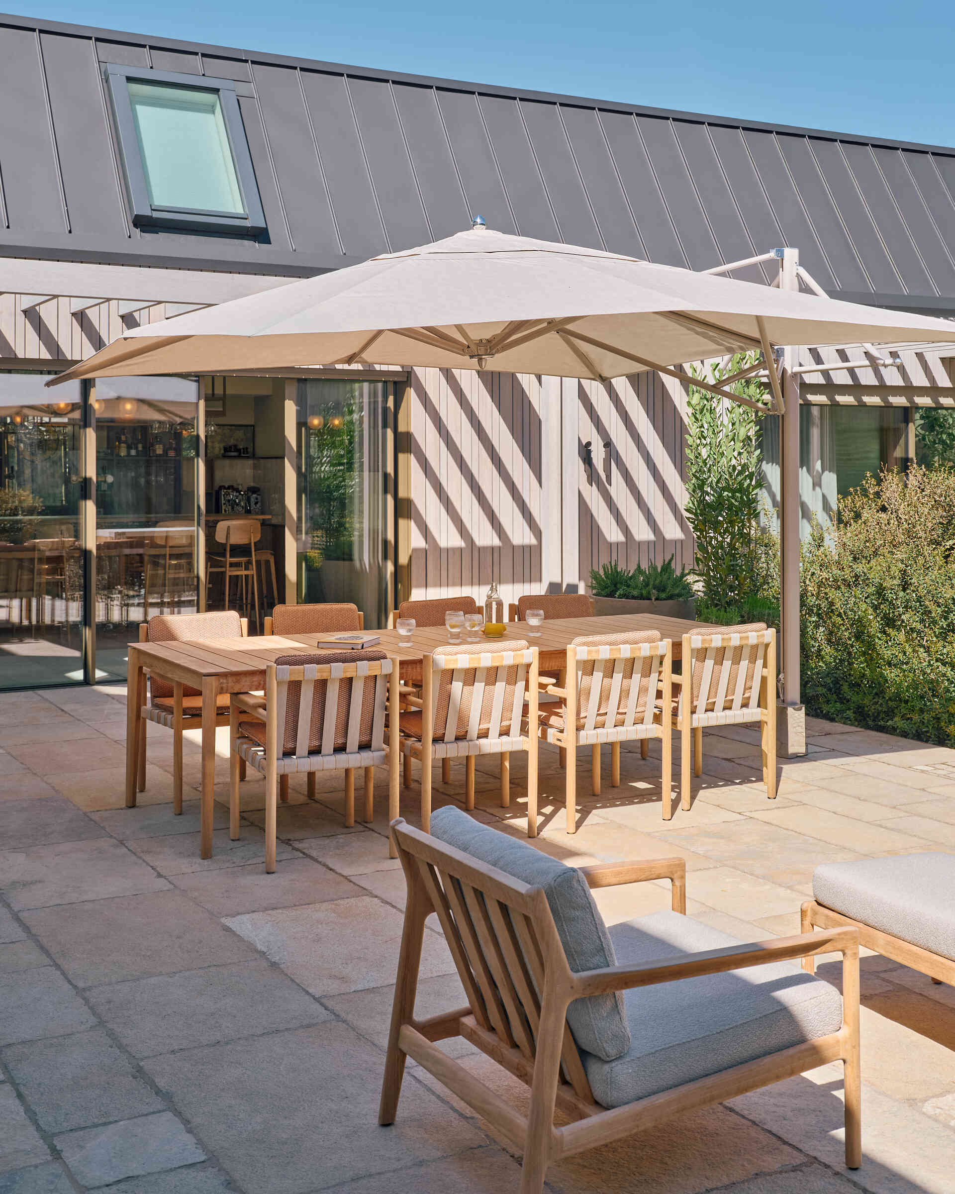 This landscaped riverside garden features outdoor dining zones, light furniture, and beautiful views stretching across the Rijn.