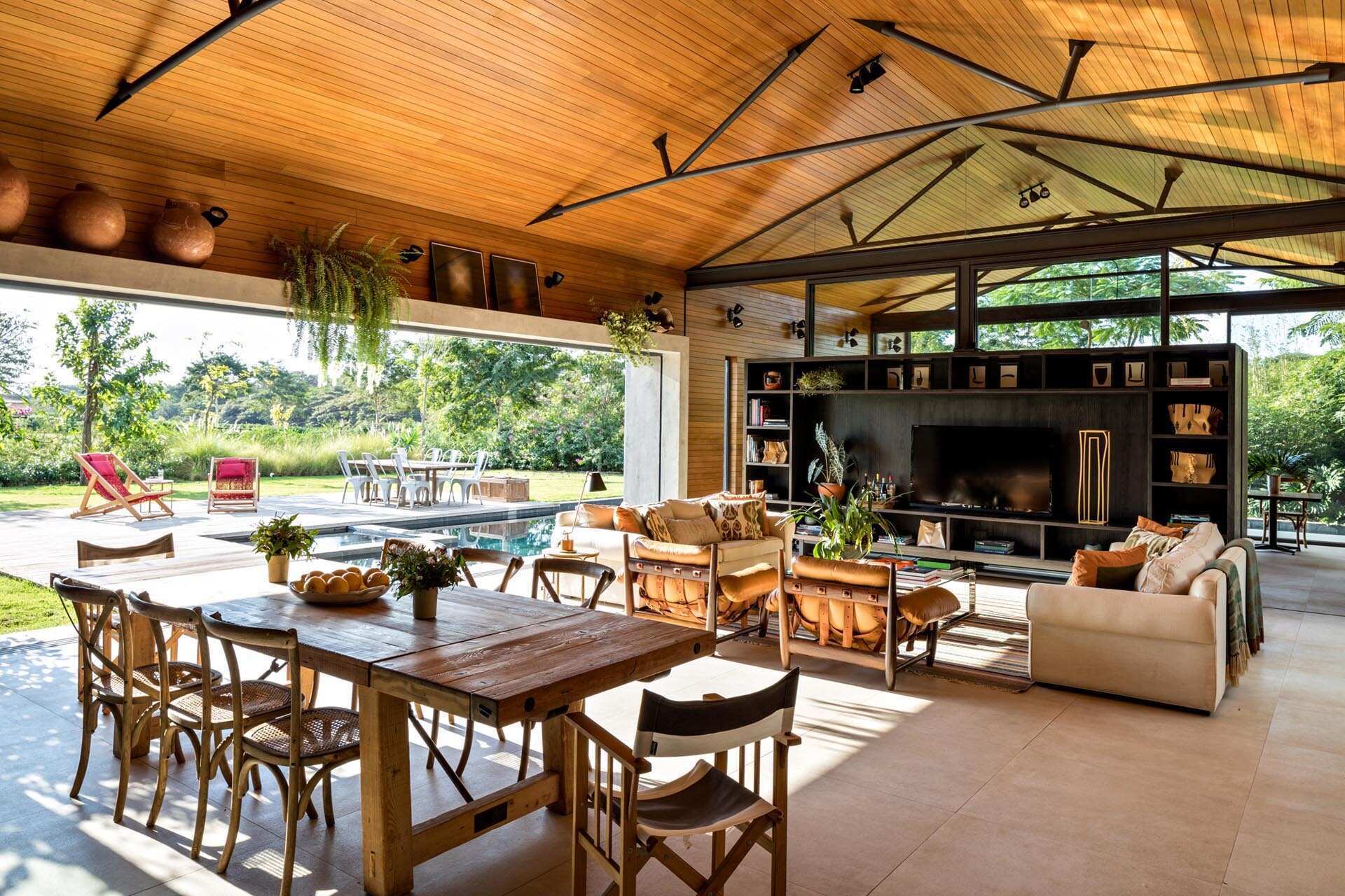 A custom wood and steel divider creates two connected living spaces, blending openness with structure and adding built-in shelving with a TV feature.