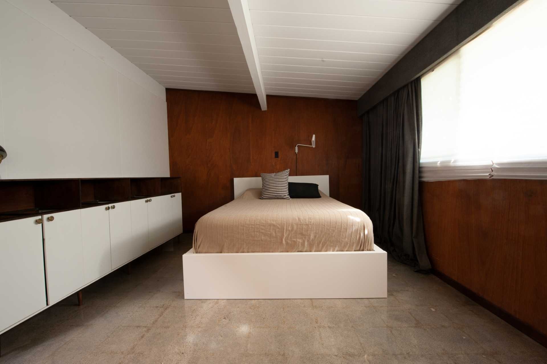 BEFORE - A compact 42-square-foot ensuite tucked into a San Jose Eichler bedroom, opening out to a private patio with an outdoor bathtub surrounded by greenery and black fencing.