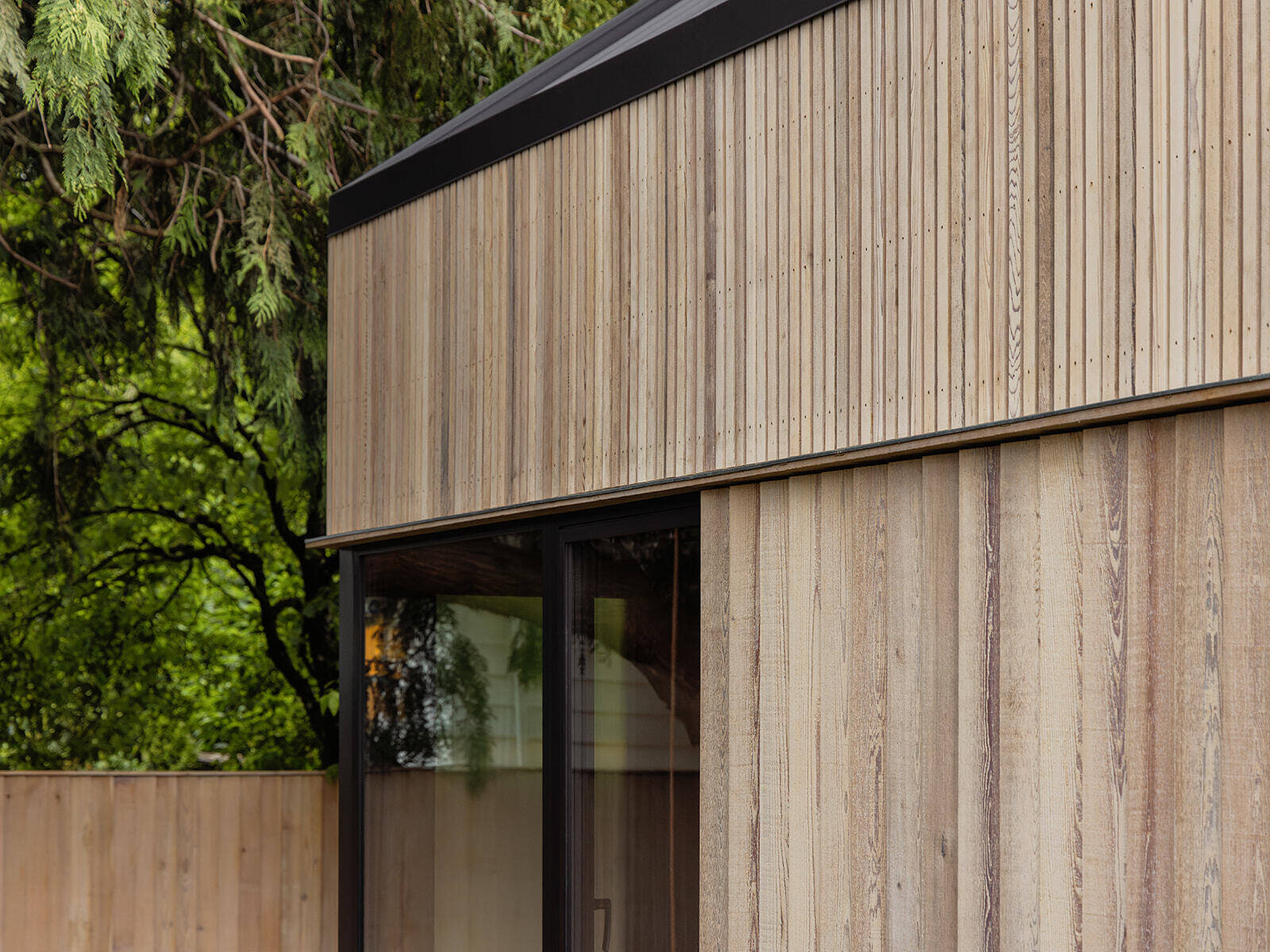 This cedar-clad bathhouse in Portland, Oregon transforms the footprint of a 100-year-old carriage house into a striking modern backyard spa. Designed by Ment Architecture with landscape design by Planterra Design, the project combines custom cedar siding, black steel details, lush layered planting, bluestone patios, and moody garden spaces inspired by Portland’s rainy winters.