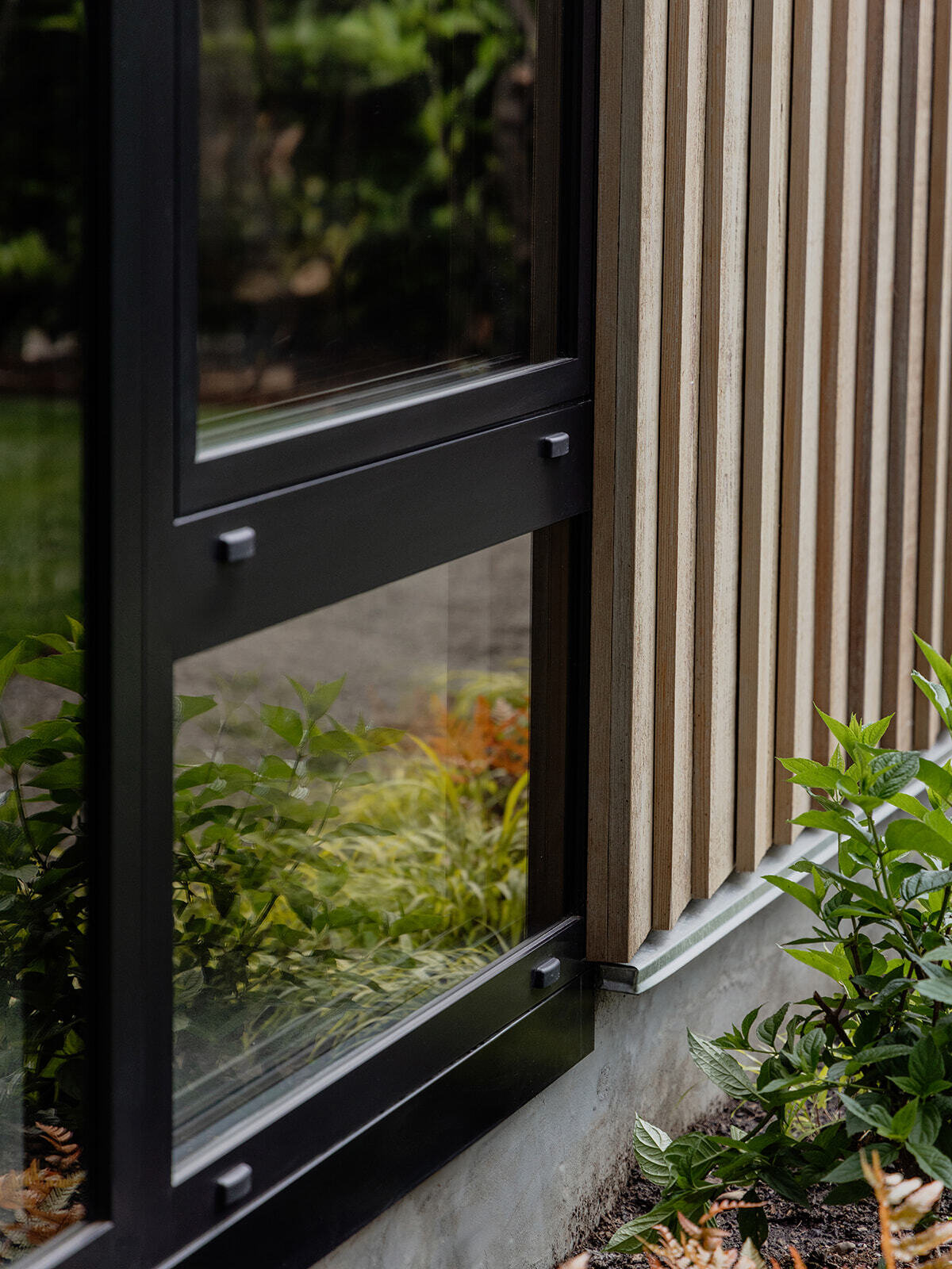 This cedar-clad bathhouse in Portland, Oregon transforms the footprint of a 100-year-old carriage house into a striking modern backyard spa. Designed by Ment Architecture with landscape design by Planterra Design, the project combines custom cedar siding, black steel details, lush layered planting, bluestone patios, and moody garden spaces inspired by Portland’s rainy winters.