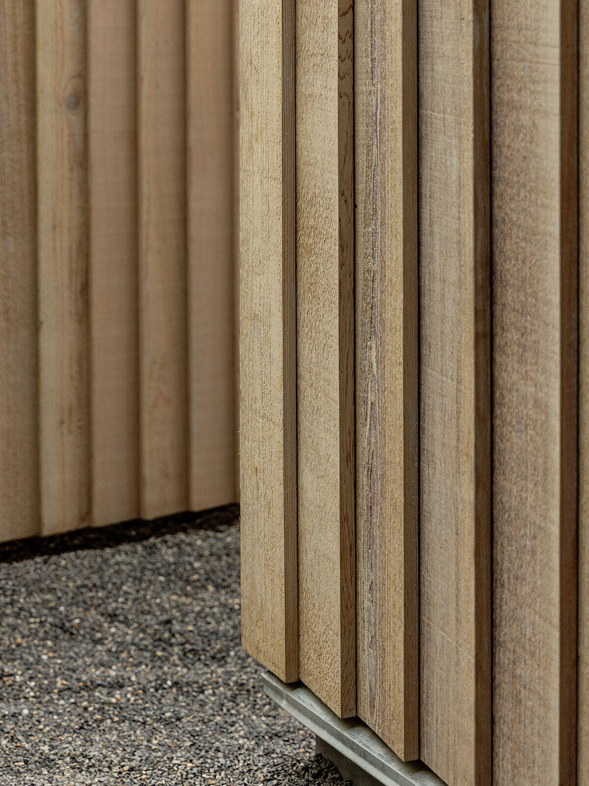This cedar-clad bathhouse in Portland, Oregon transforms the footprint of a 100-year-old carriage house into a striking modern backyard spa. Designed by Ment Architecture with landscape design by Planterra Design, the project combines custom cedar siding, black steel details, lush layered planting, bluestone patios, and moody garden spaces inspired by Portland’s rainy winters.