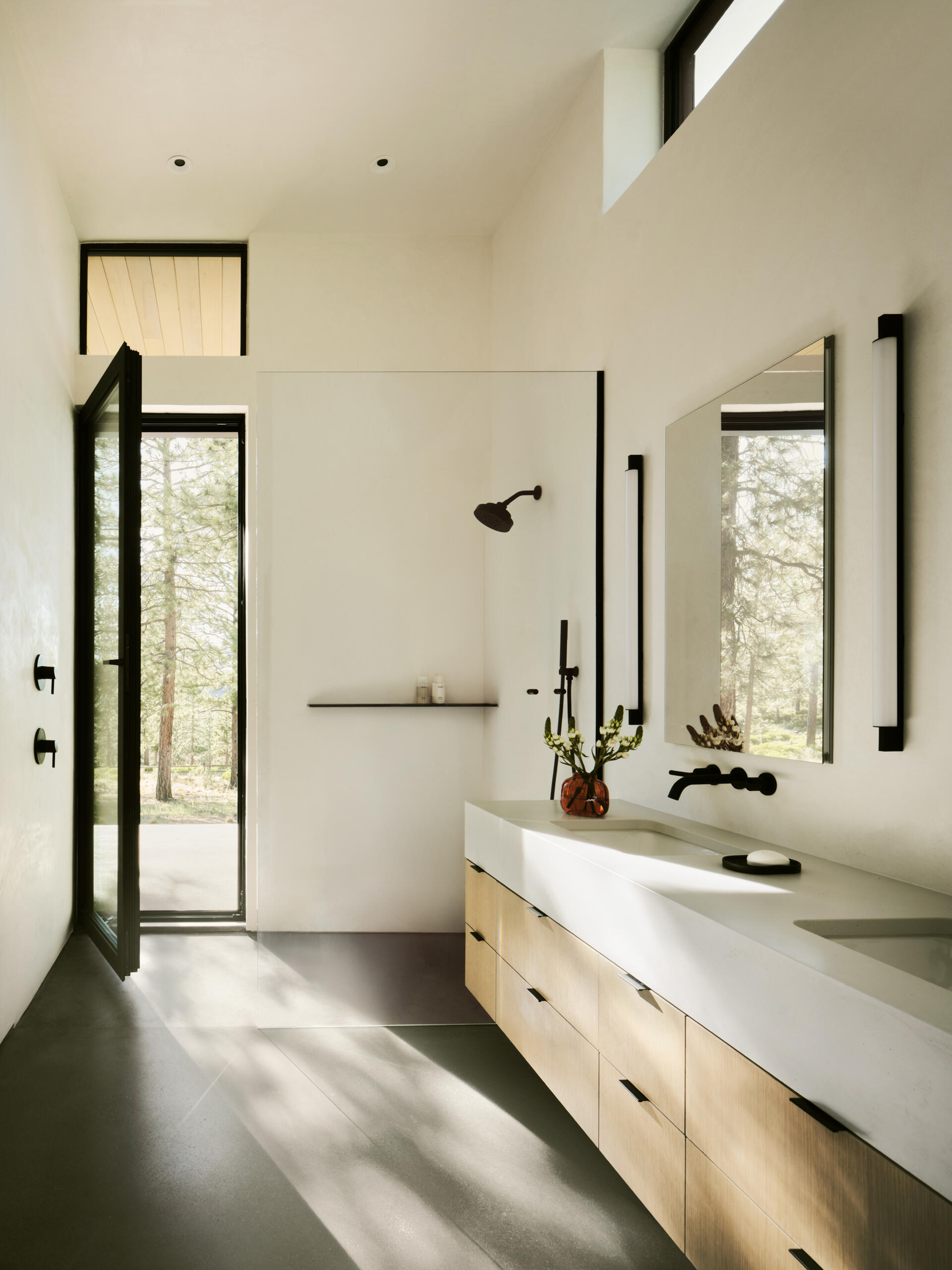 Concrete floors, warm wood, and soft natural light create beautifully minimal bathrooms inside this modern Bend, Oregon home.
