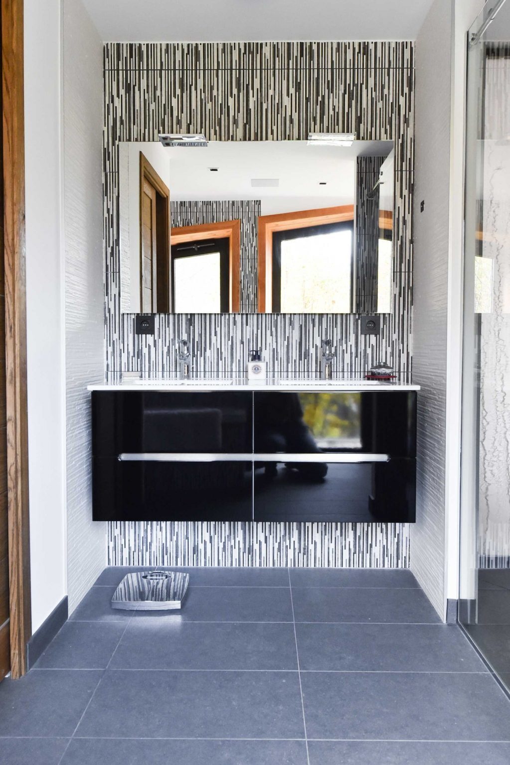 In this bathroom, a vertically patterned accent wall introduces depth and contrast while maintaining the restrained material palette found throughout the home.