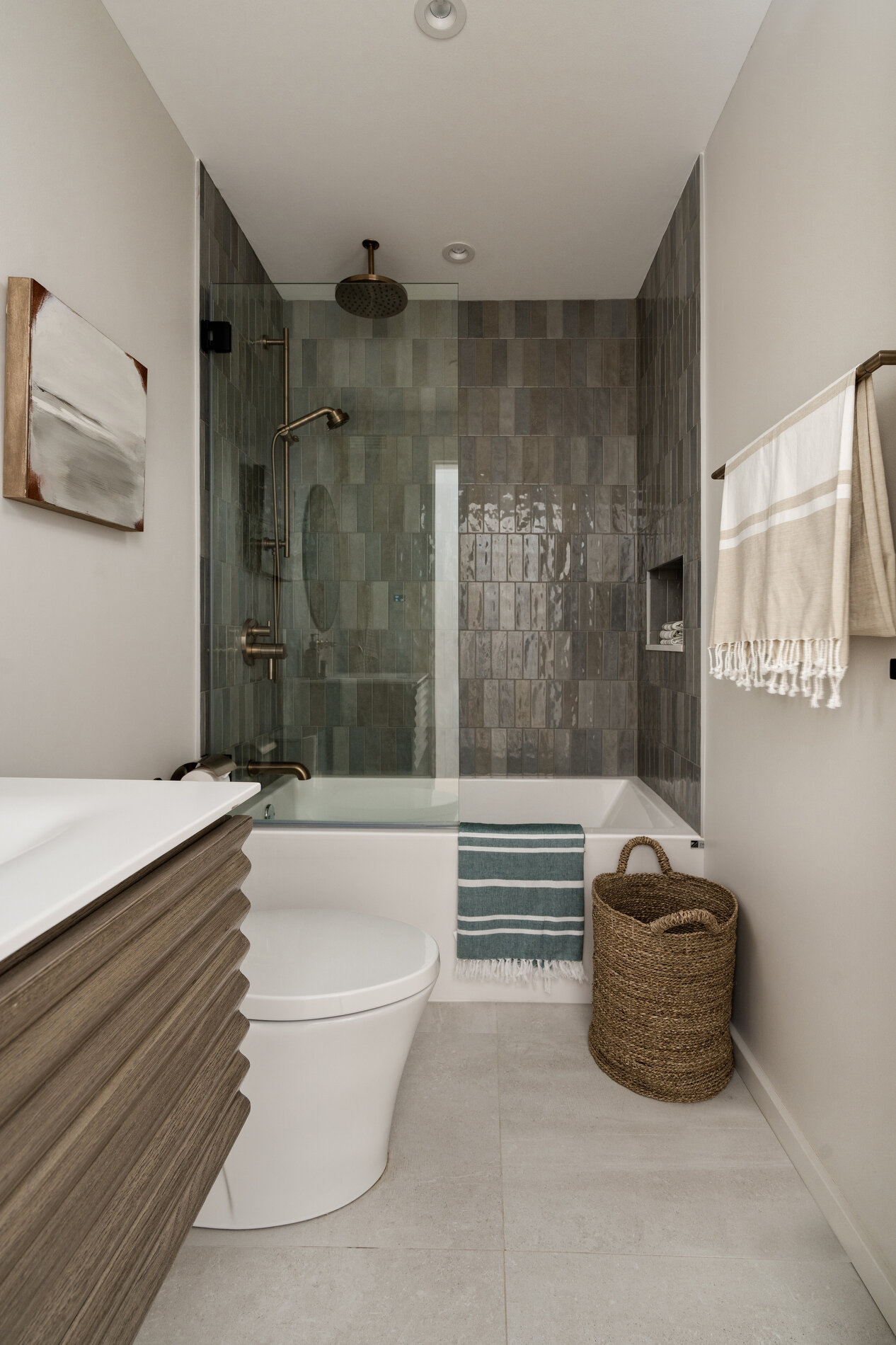 A modern bathroom with vertical tiles and a recessed shelving niche.