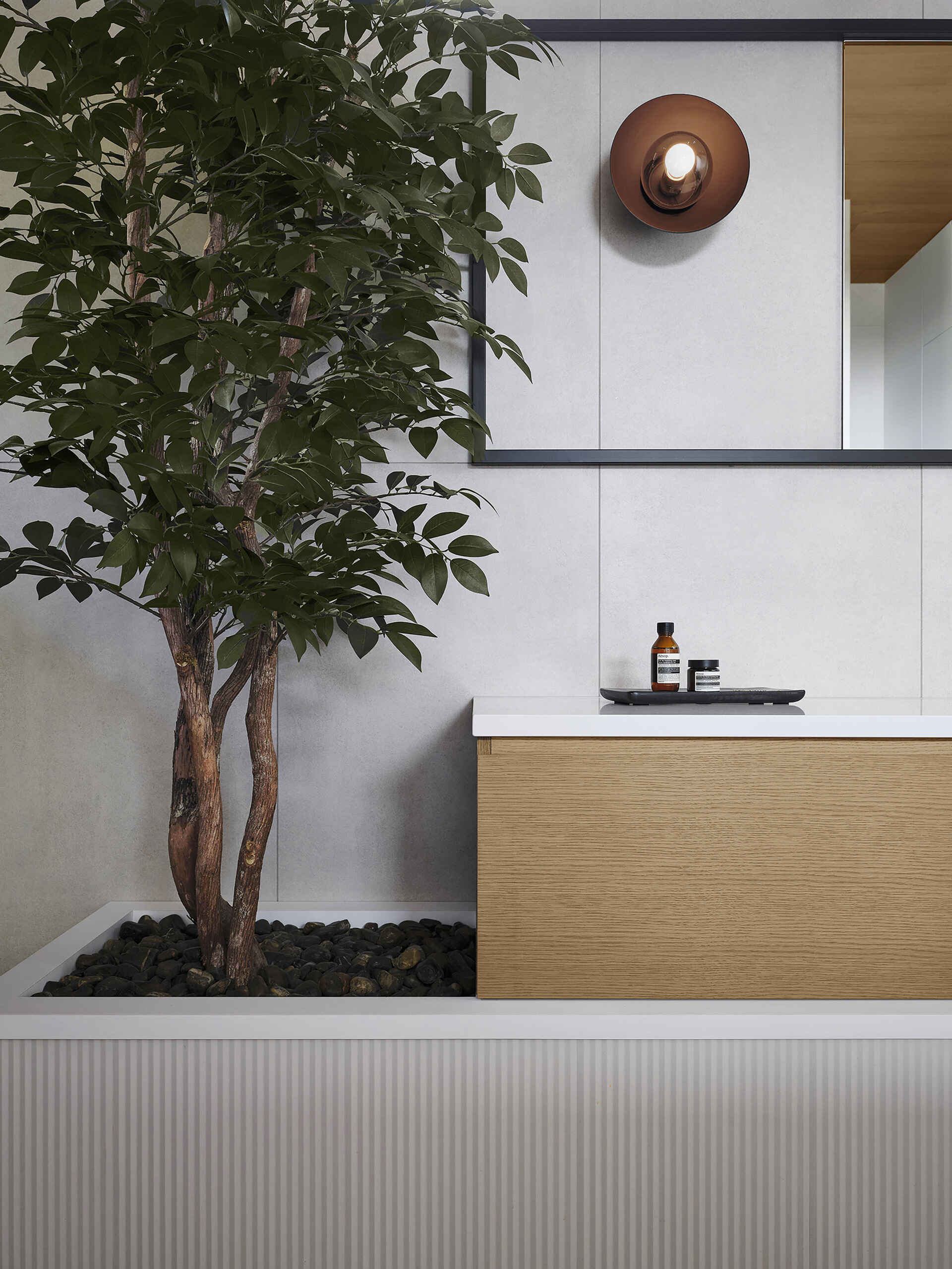 The bathroom features a pair of vanities, integrated lighting, and a wet room with dark tile surfaces and a glass wall that separates it from the rest of the room. The use of natural materials helps the spaces feel consistent with the rest of the residence while still maintaining a quieter atmosphere.
