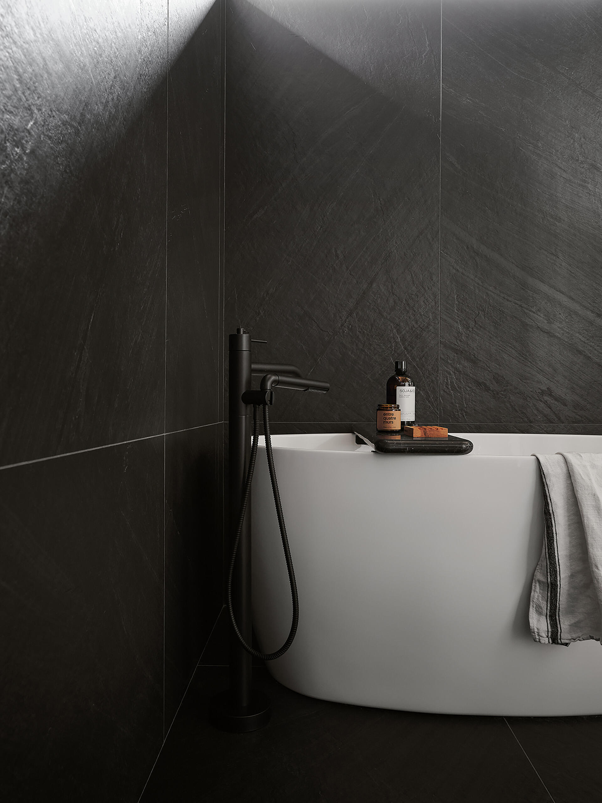 The bathroom features a pair of vanities, integrated lighting, and a wet room with dark tile surfaces and a glass wall that separates it from the rest of the room. The use of natural materials helps the spaces feel consistent with the rest of the residence while still maintaining a quieter atmosphere.