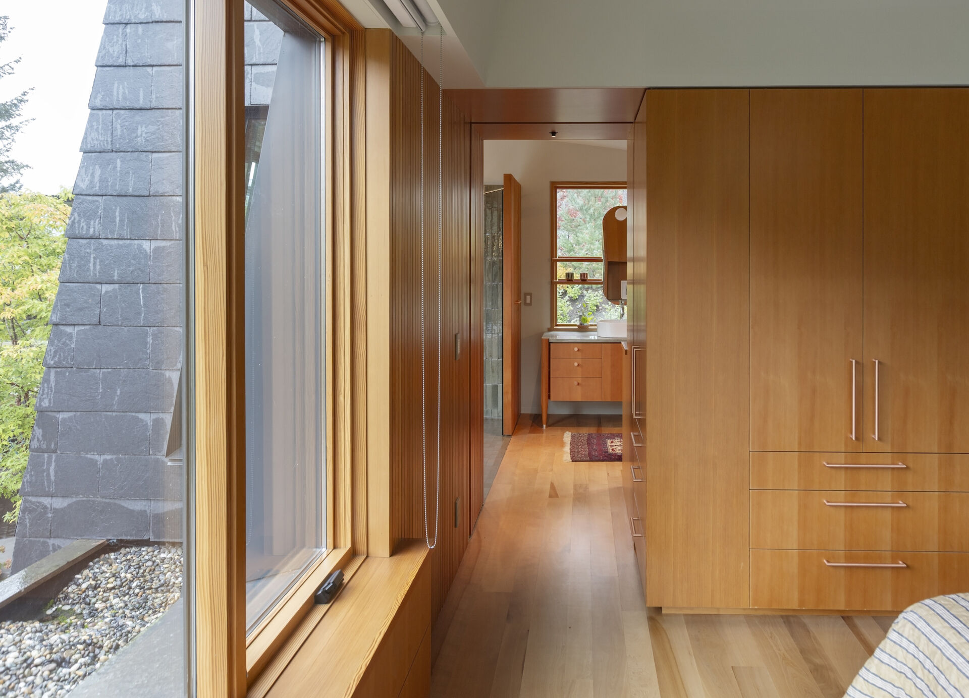 Fluted wood vanities, slatted screens, and warm natural finishes give this bathroom a refined mountain cabin feel.