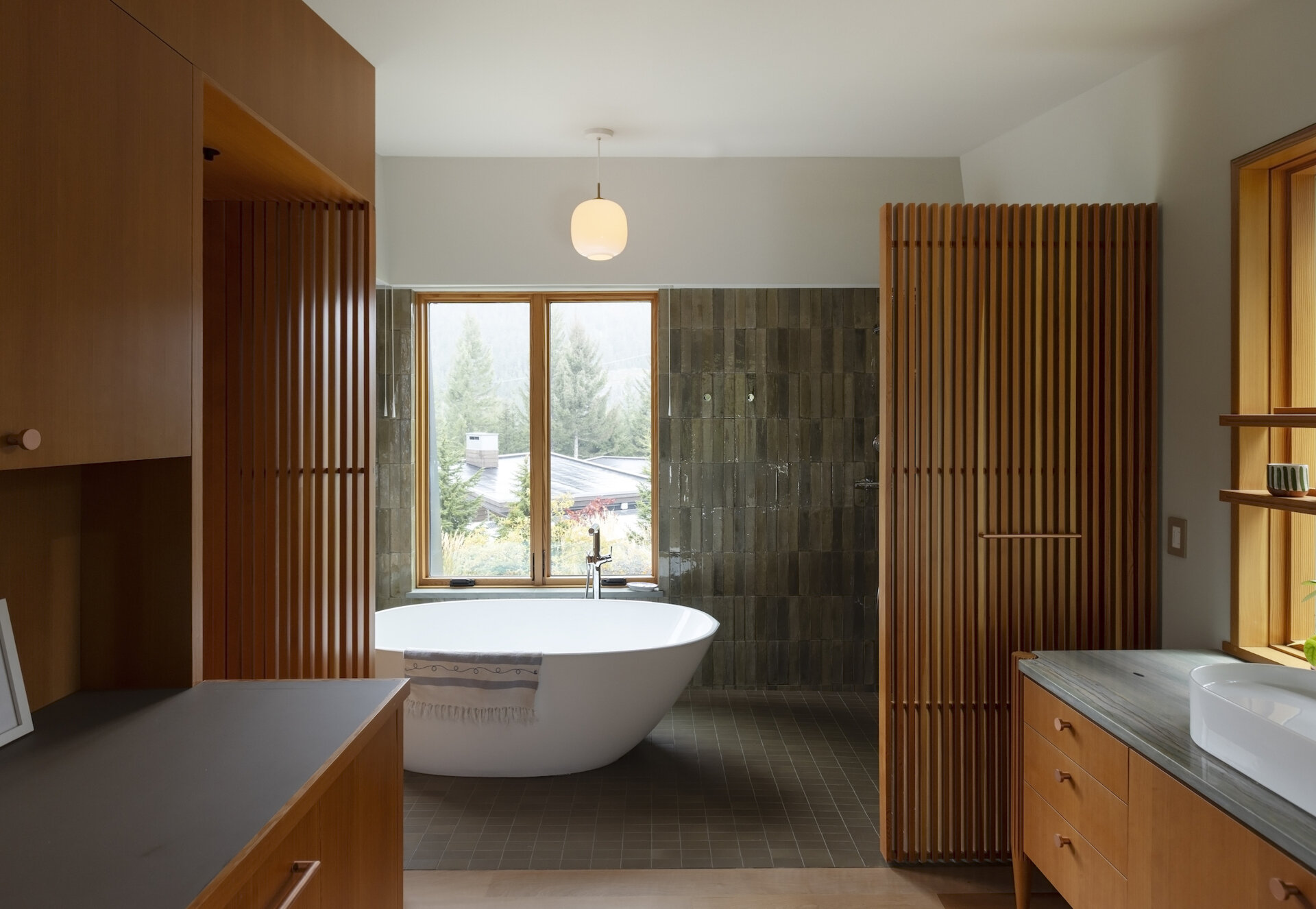 Fluted wood vanities, slatted screens, and warm natural finishes give this bathroom a refined mountain cabin feel.