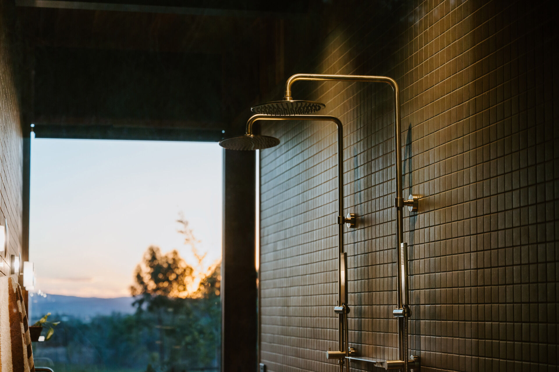 A modern off-grid cabin with rammed earth walls and sage green square tiles in the bathroom.