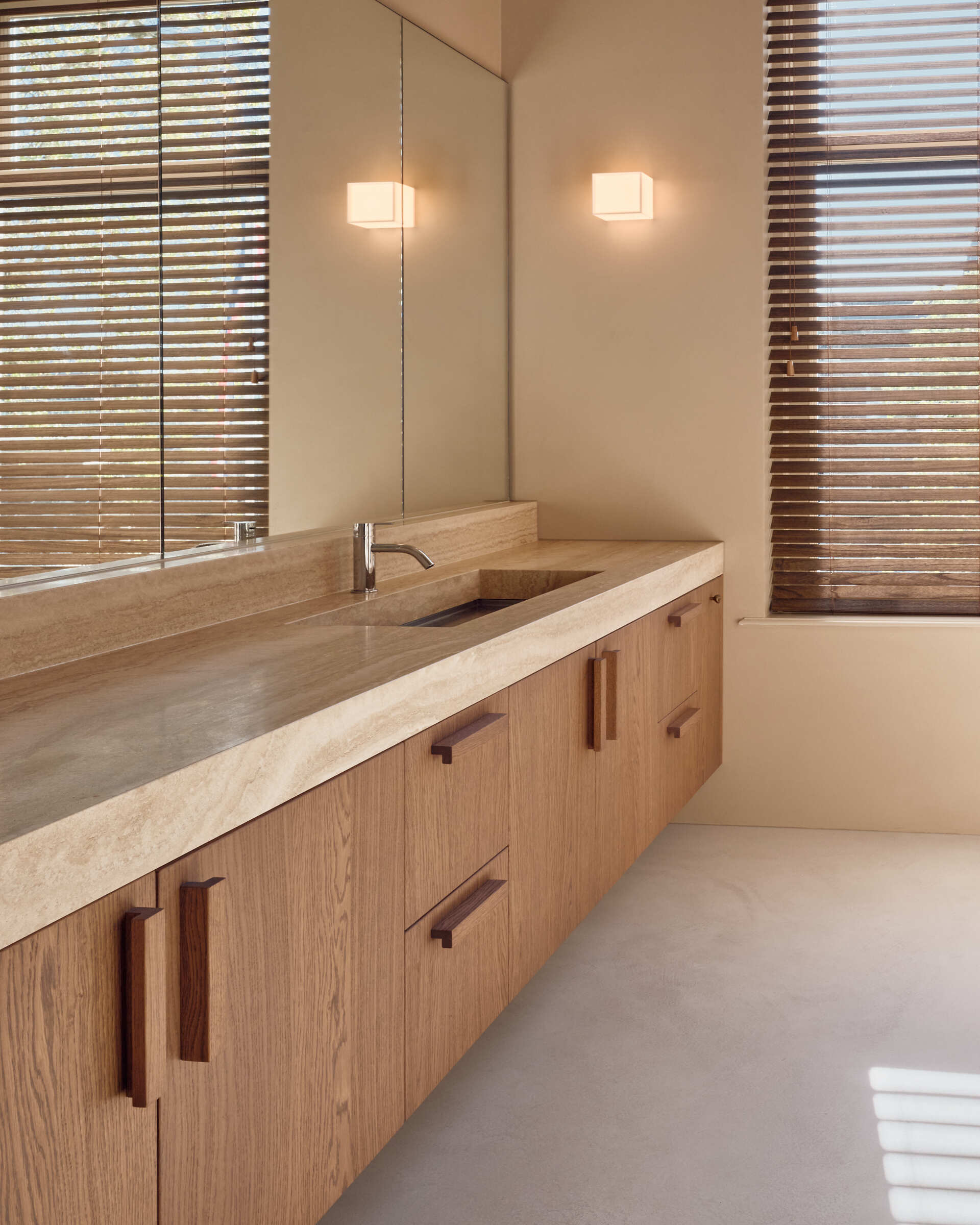 This light-filled bathroom combines travertine finishes, soft neutral tones, and peaceful views across the Rijn.