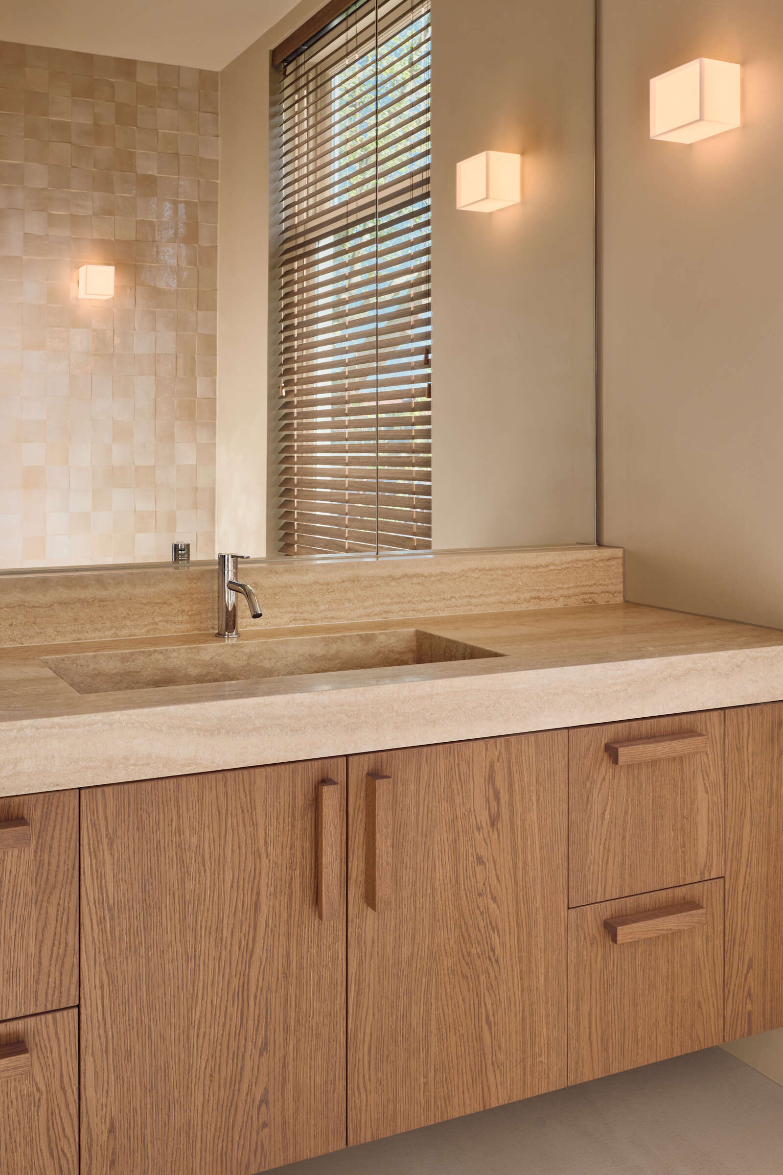 This light-filled bathroom combines travertine finishes, soft neutral tones, and peaceful views across the Rijn.