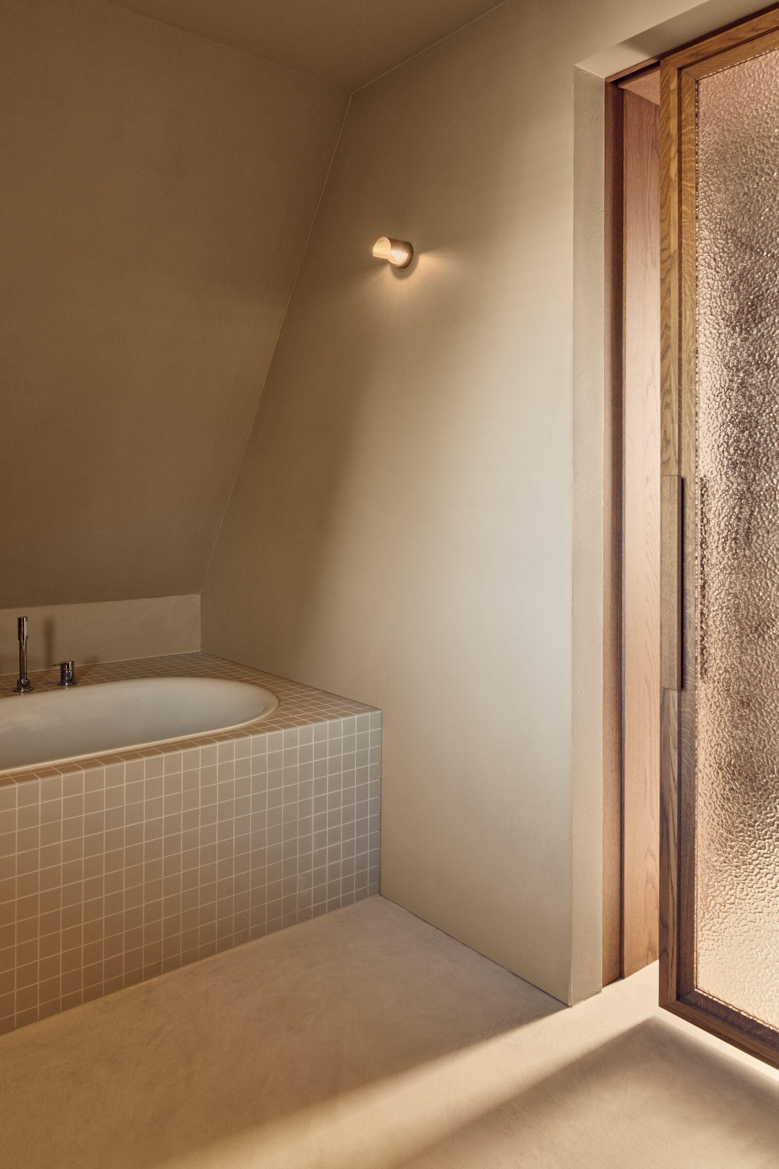 This light-filled bathroom combines travertine finishes, soft neutral tones, and peaceful views across the Rijn.