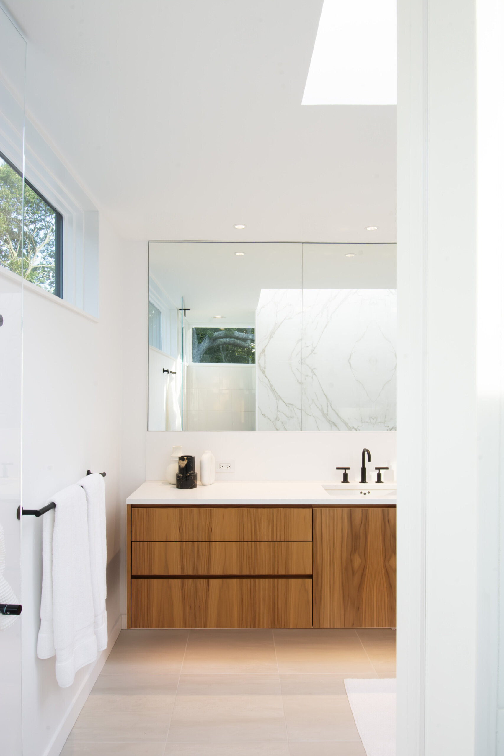Skylights and warm material finishes give this modern bathroom a bright and relaxing atmosphere.